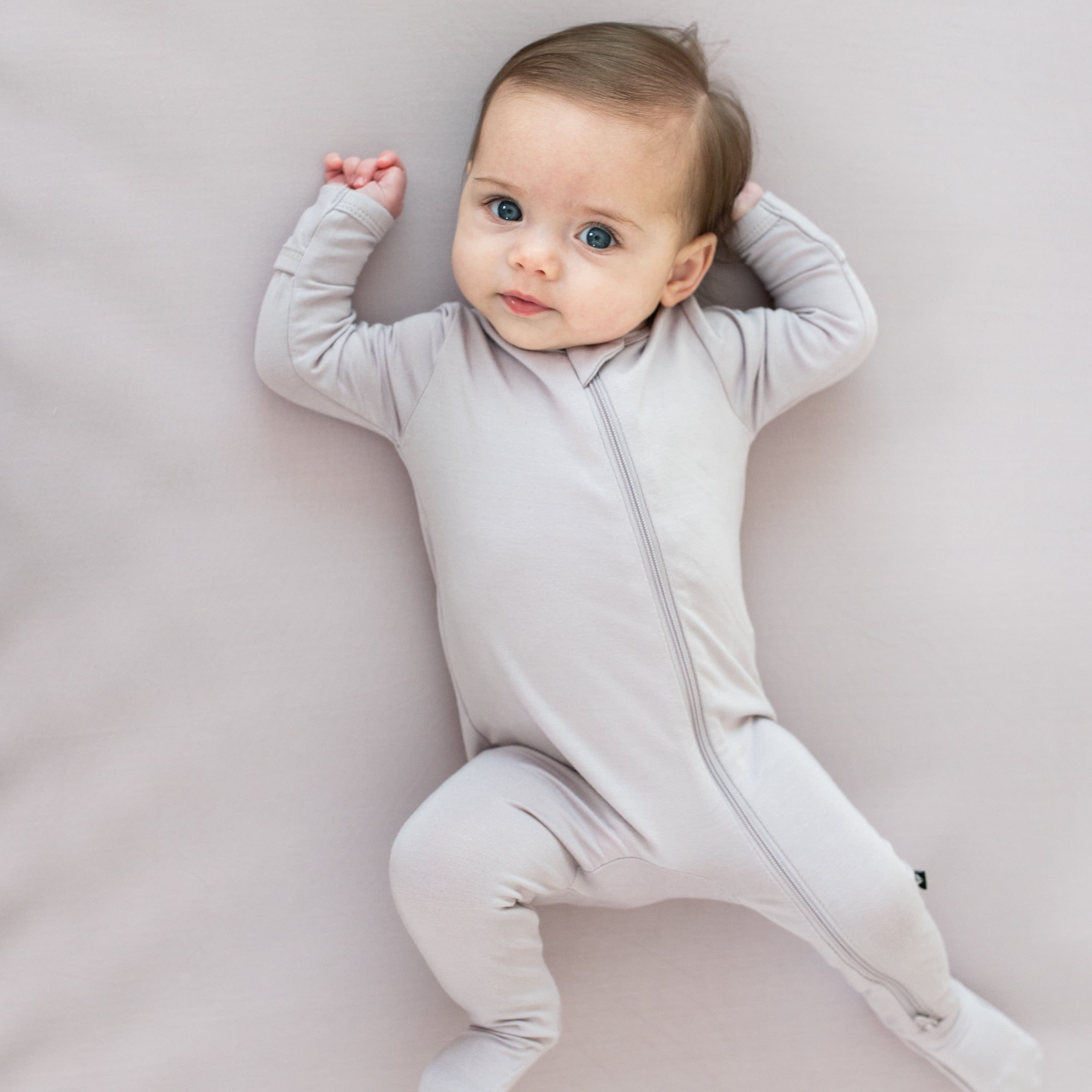 Infant wearing Kyte Baby Zippered Footie in Wisteria