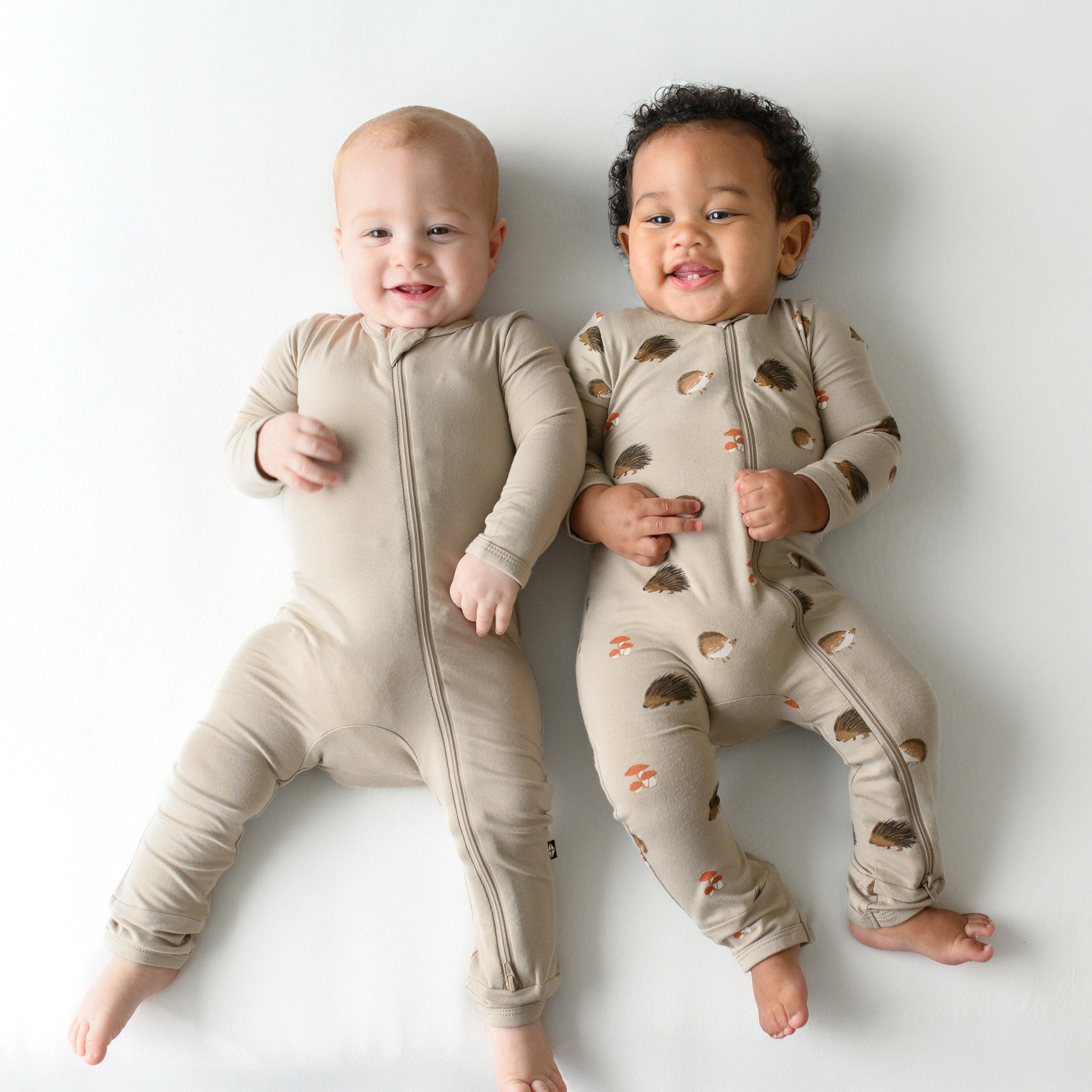 Two infant models wearing Zippered Rompers in Almond and Prickle