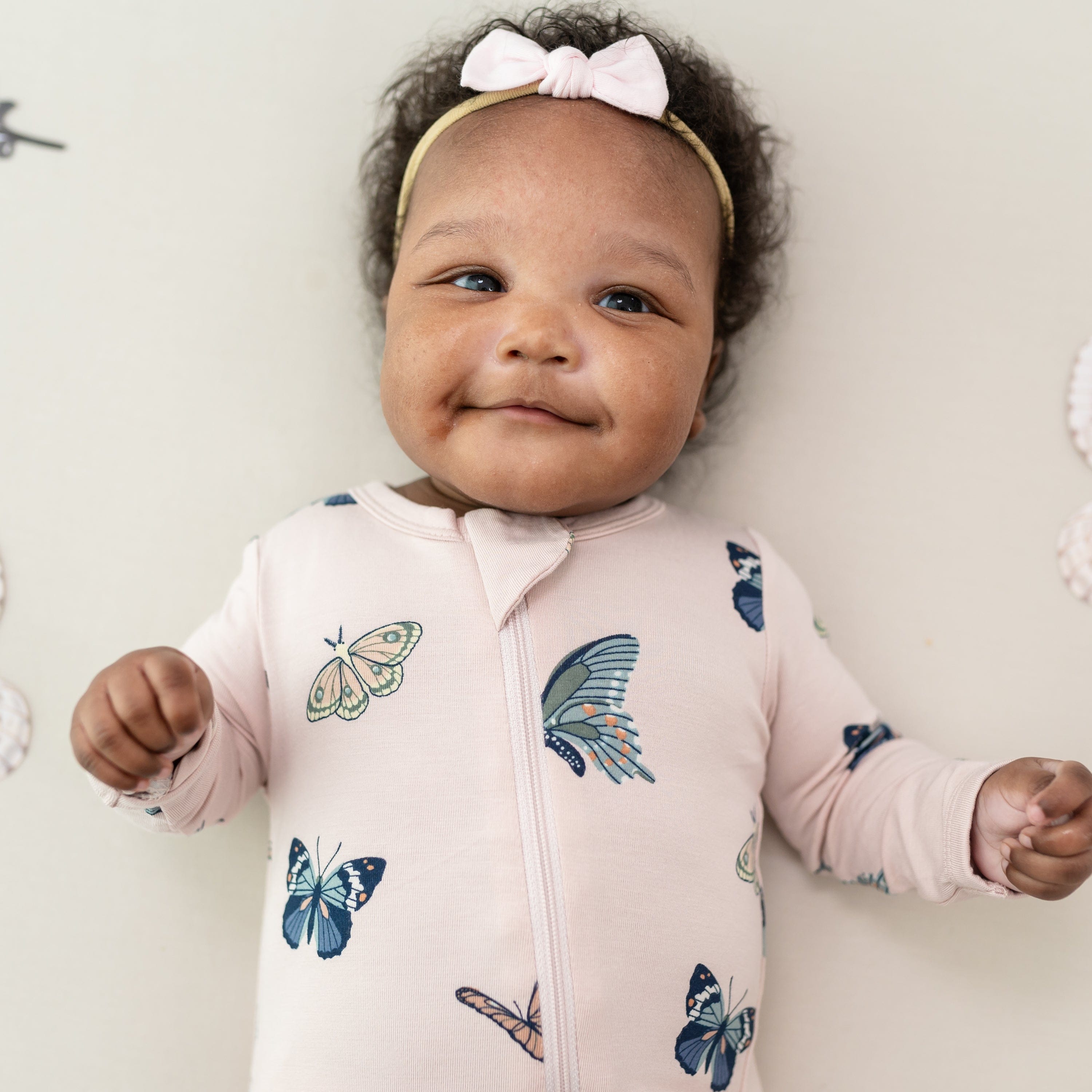 Close up of infant model wearing the Zippered Romper in Blush Butterfly