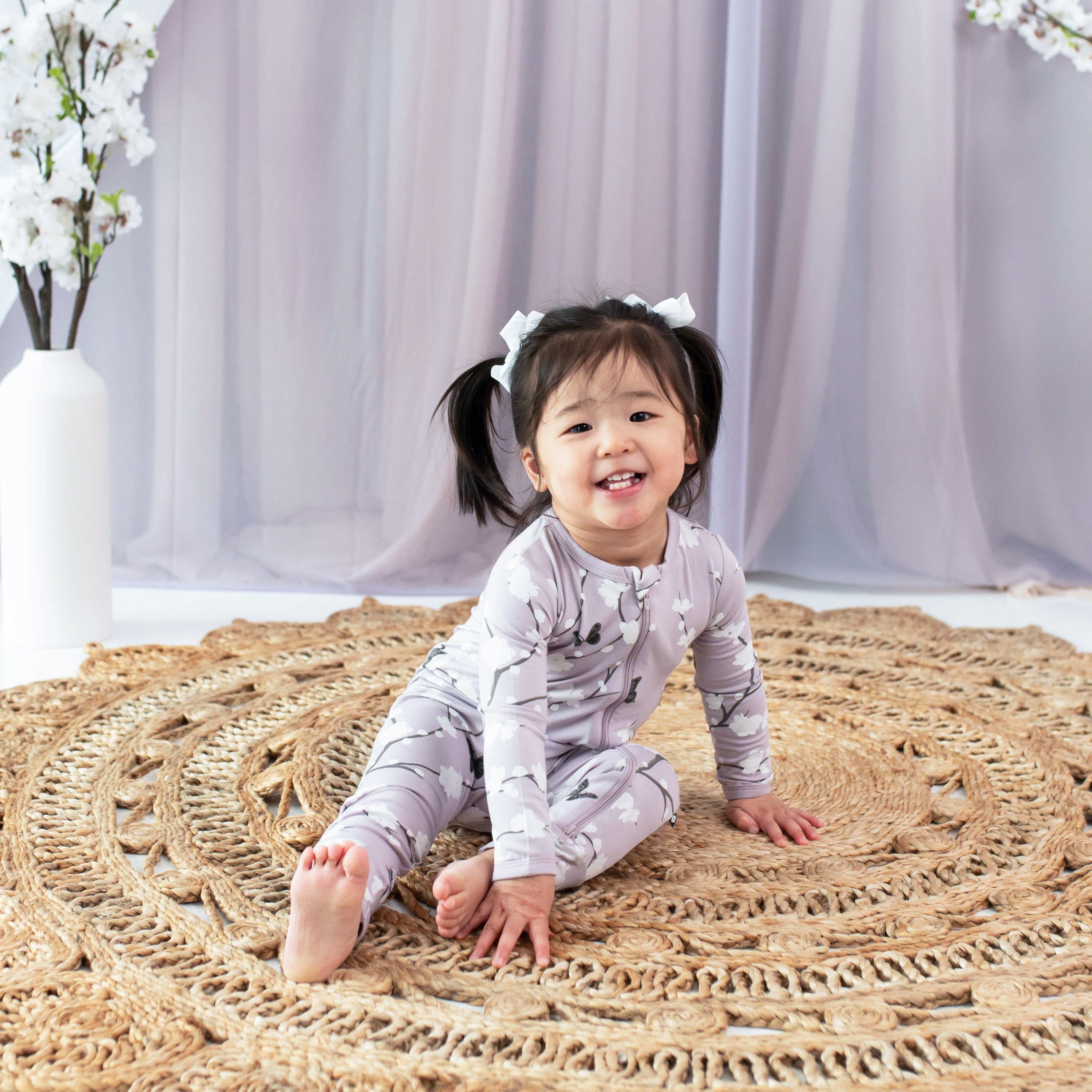 Toddler wearing Kyte Baby bamboo Zippered Romper in Cherry Blossom pattern