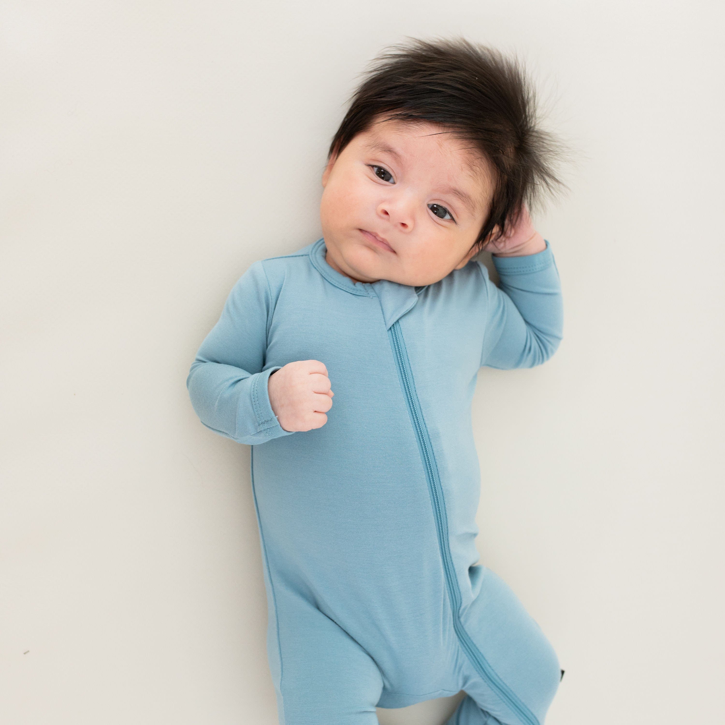 Infant wearing Kyte Baby Zippered Romper in Dusty Blue