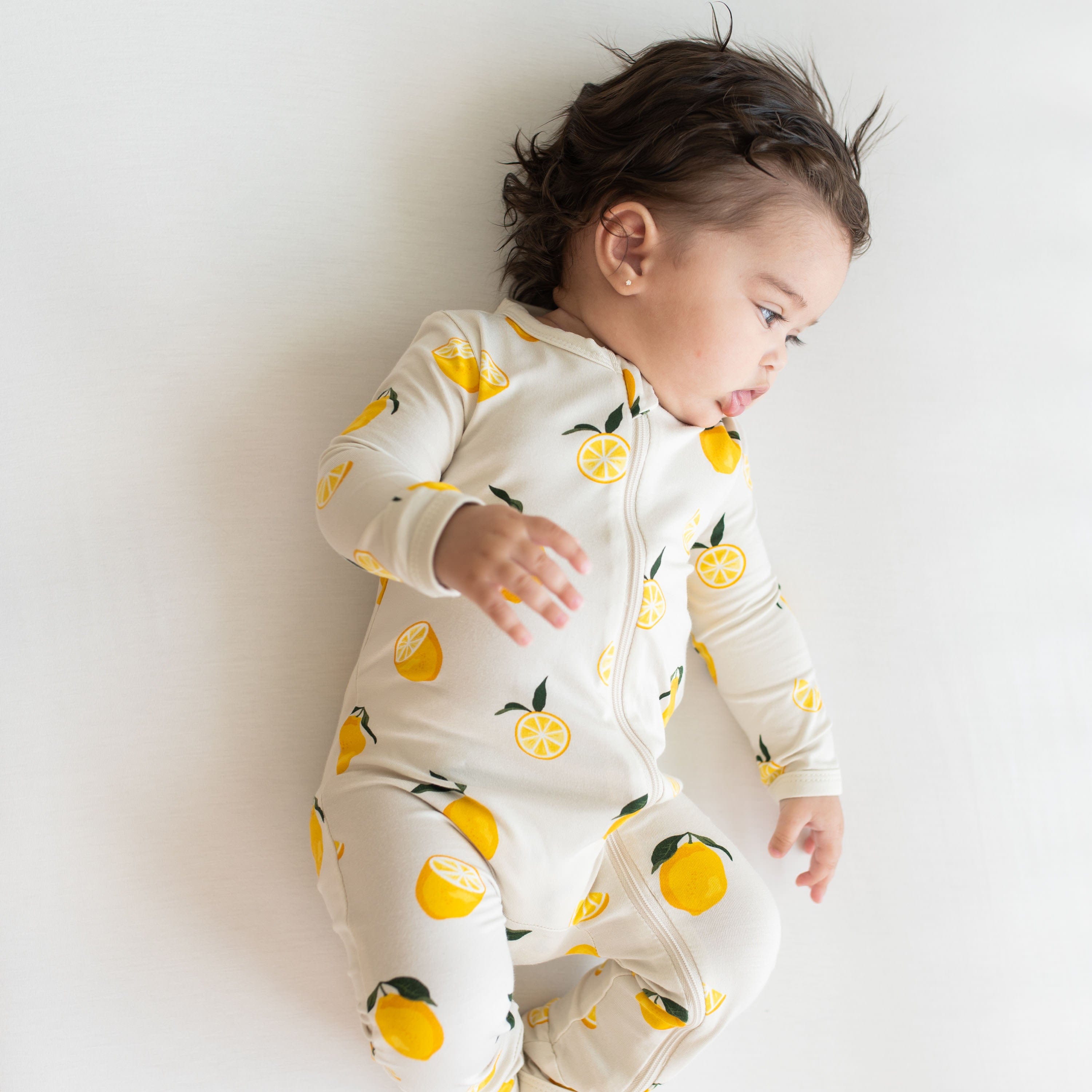 Baby wearing Kyte Baby Zippered Romper in Lemon