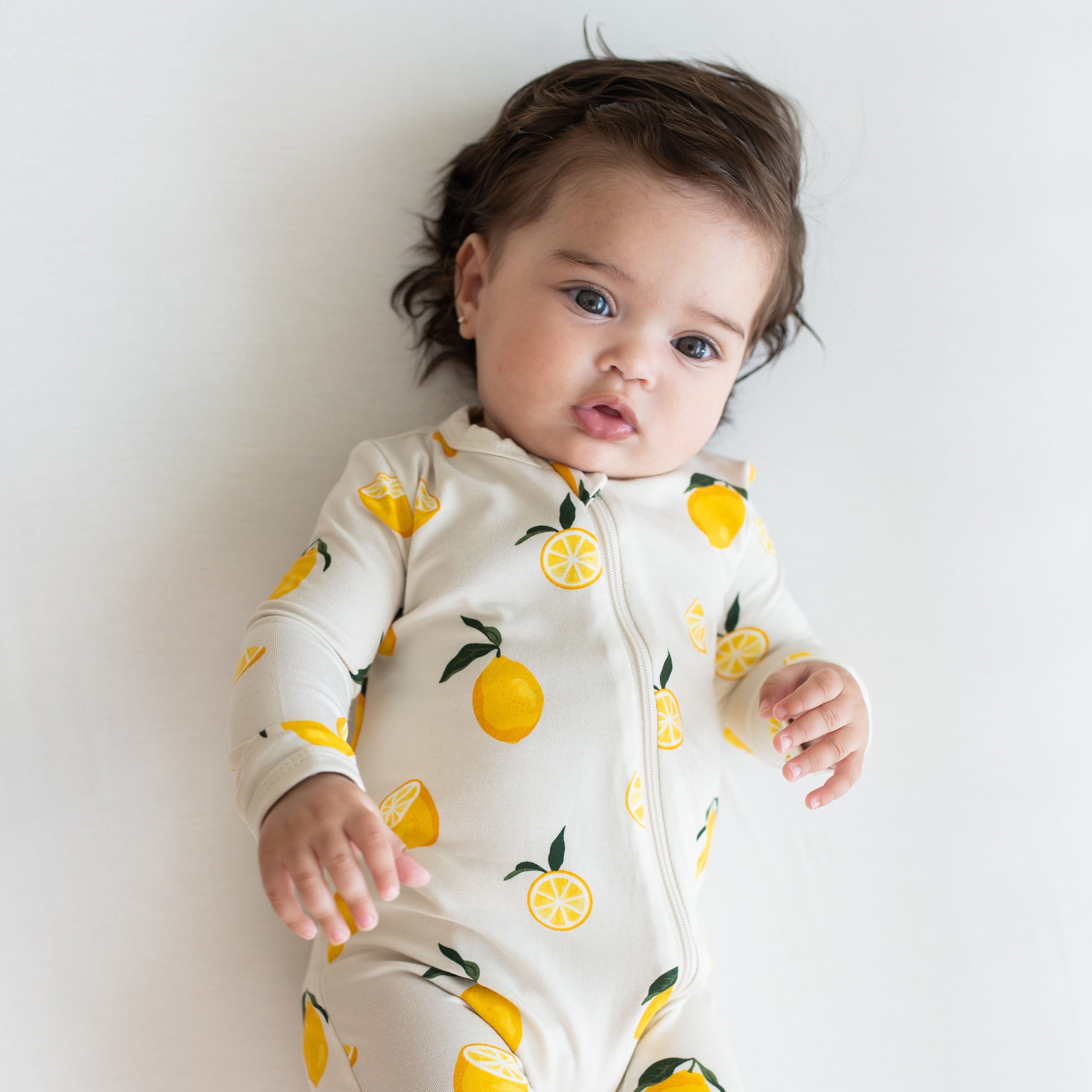 Infant wearing Kyte Baby Zippered Romper in Lemon