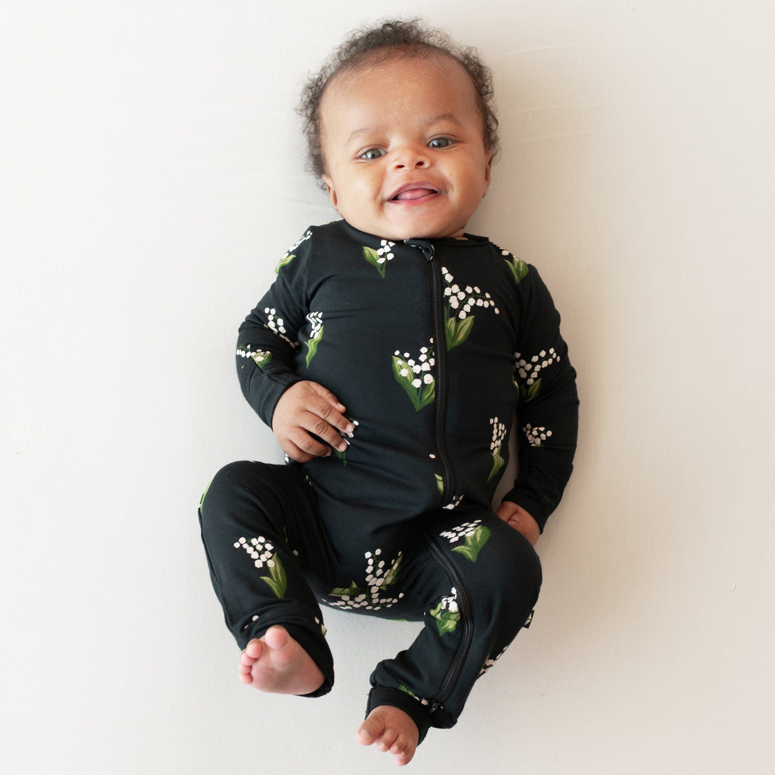 Smiling baby wearing the Zippered Romper in Midnight Lily