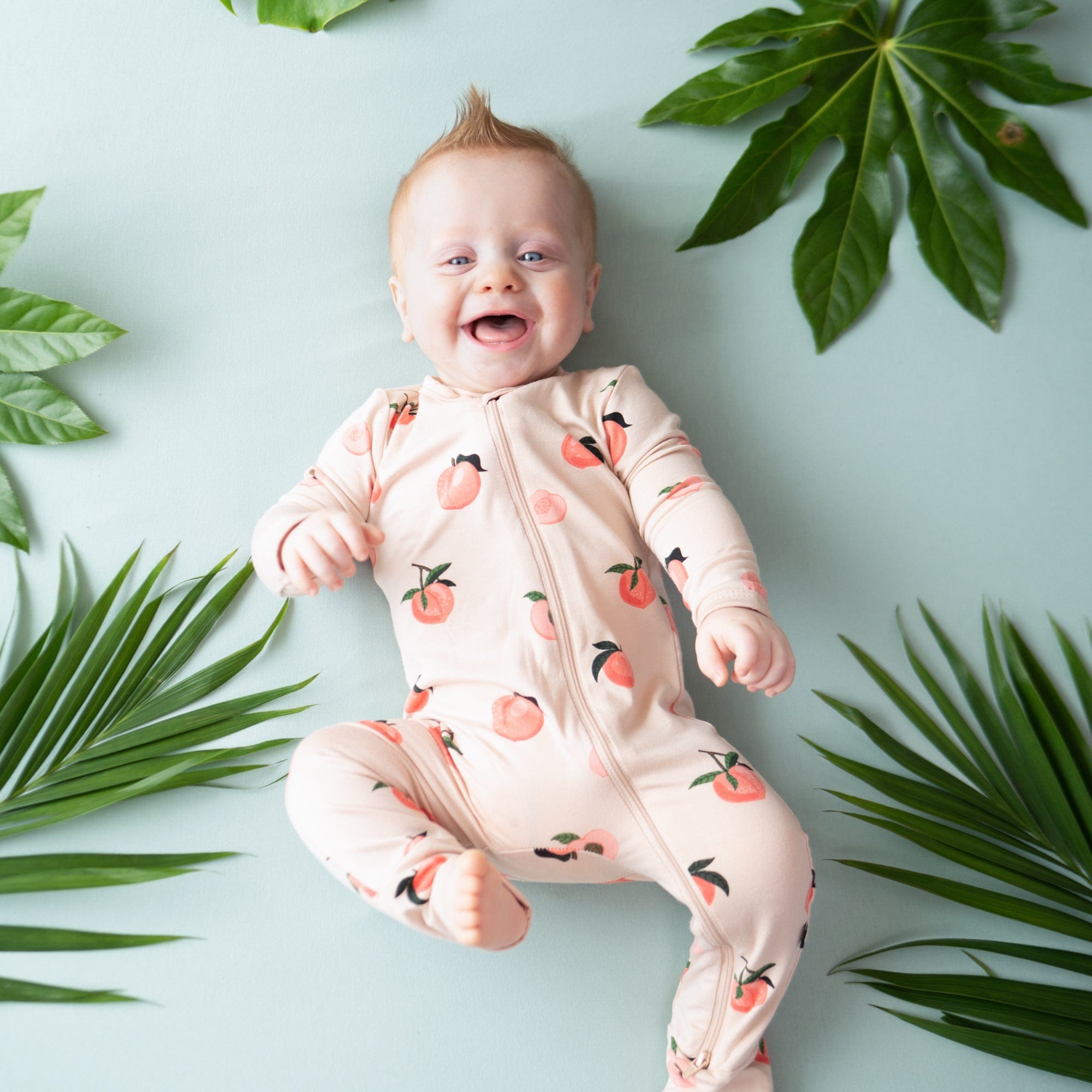 Infant wearing Kyte Baby Zippered Romper in Peach
