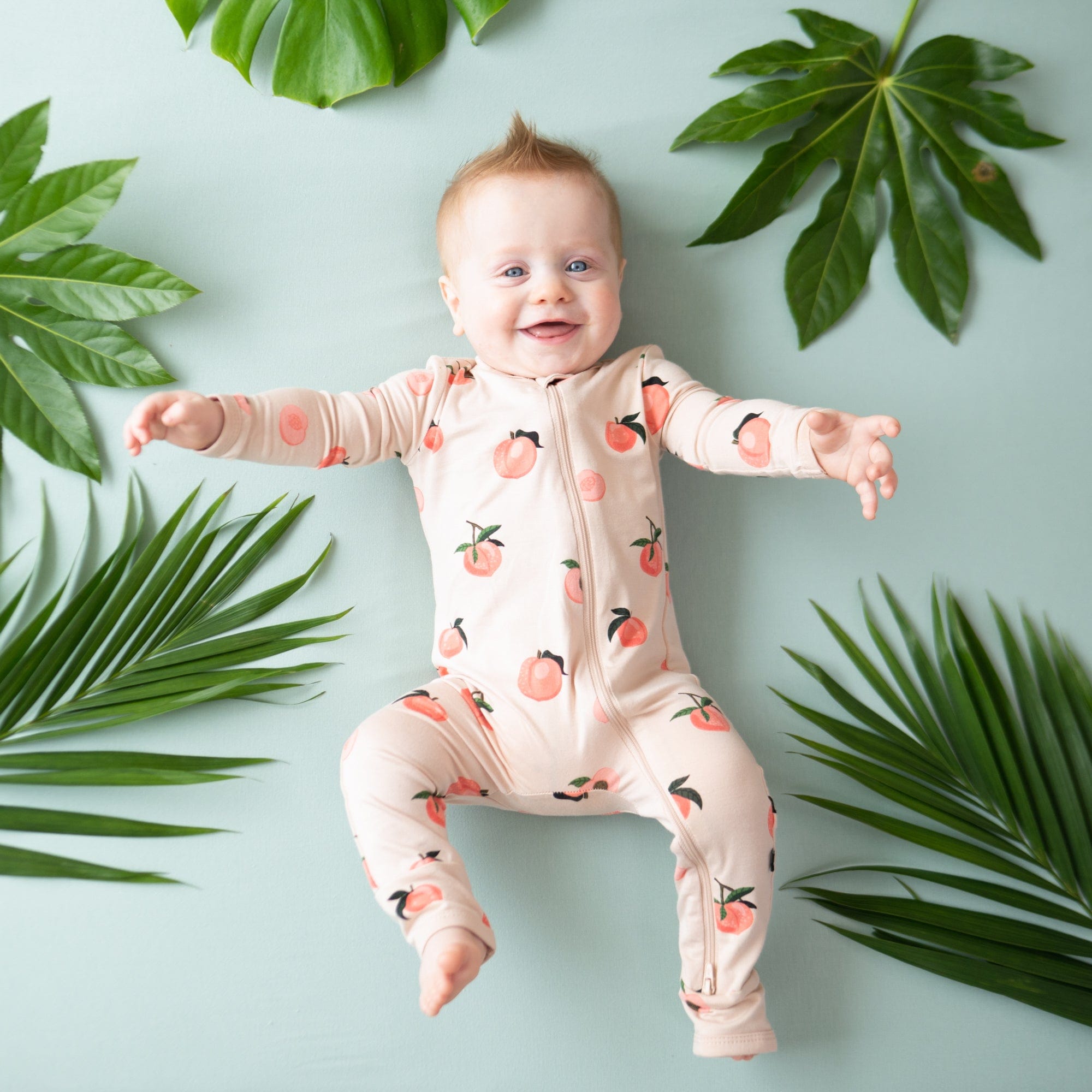 Baby wearing Kyte Baby Zippered Romper in Peach