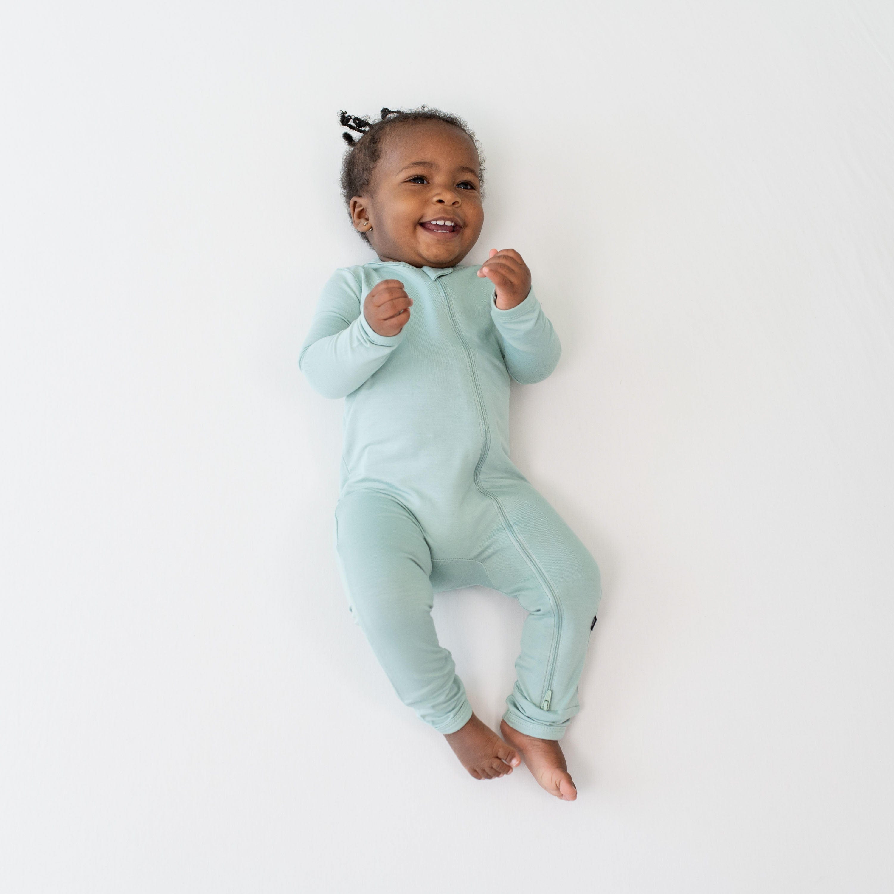 Infant model wearing a Kyte Baby Zippered Romper in Sage