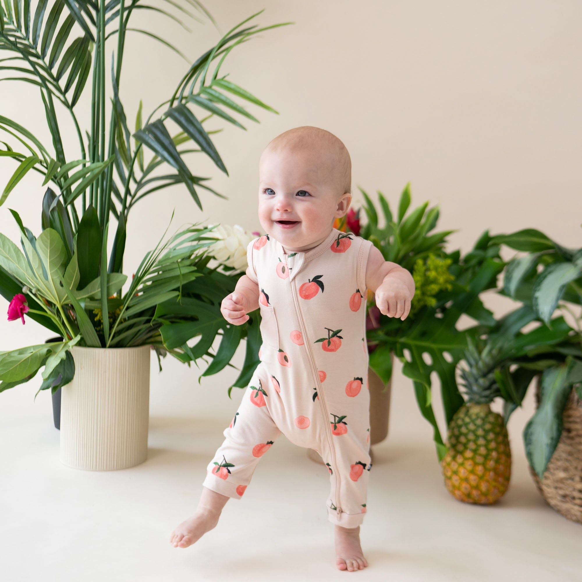 Baby wearing Kyte Baby Sleeveless Zippered Romper in Peach