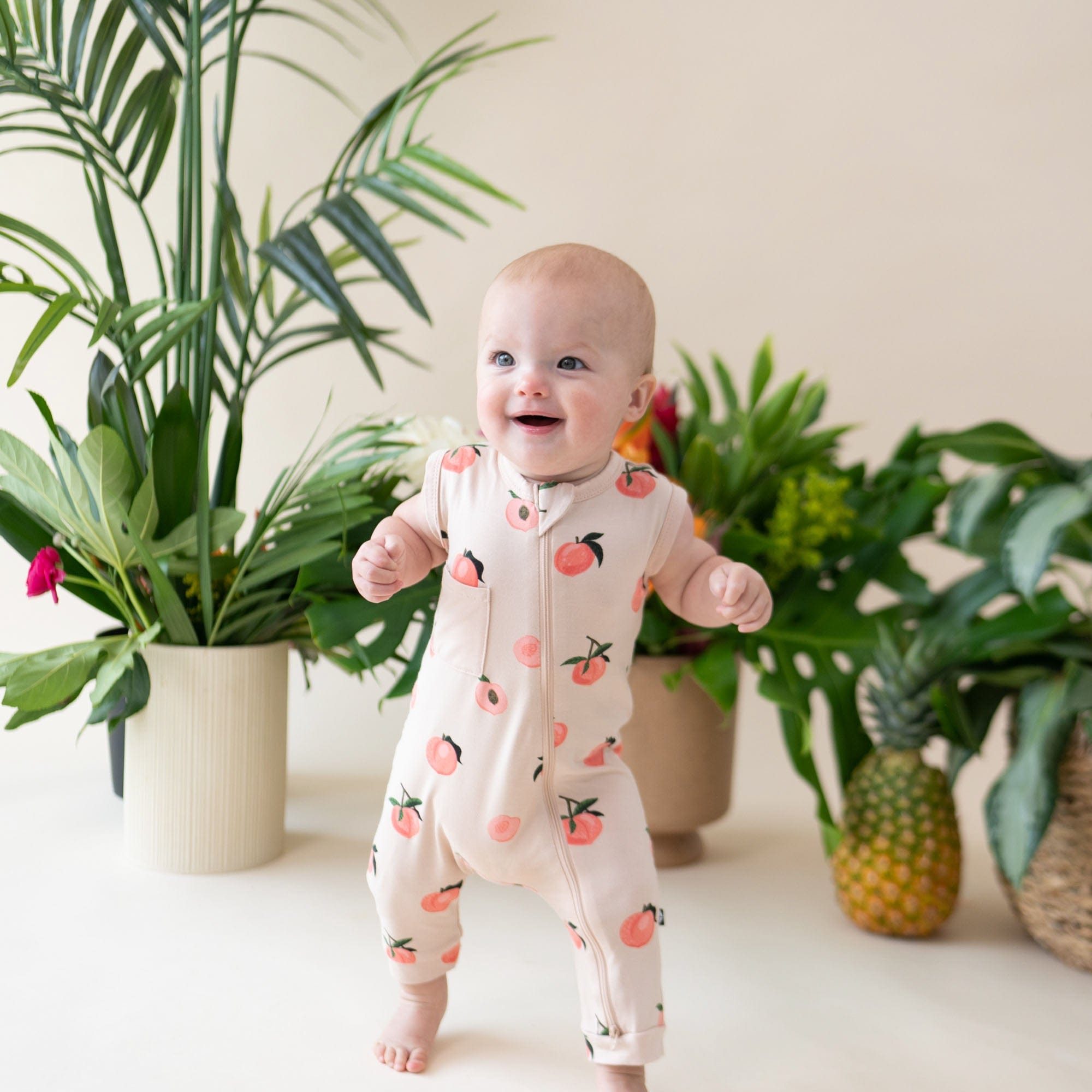 Infant wearing Kyte Baby Sleeveless Zippered Romper in Peach