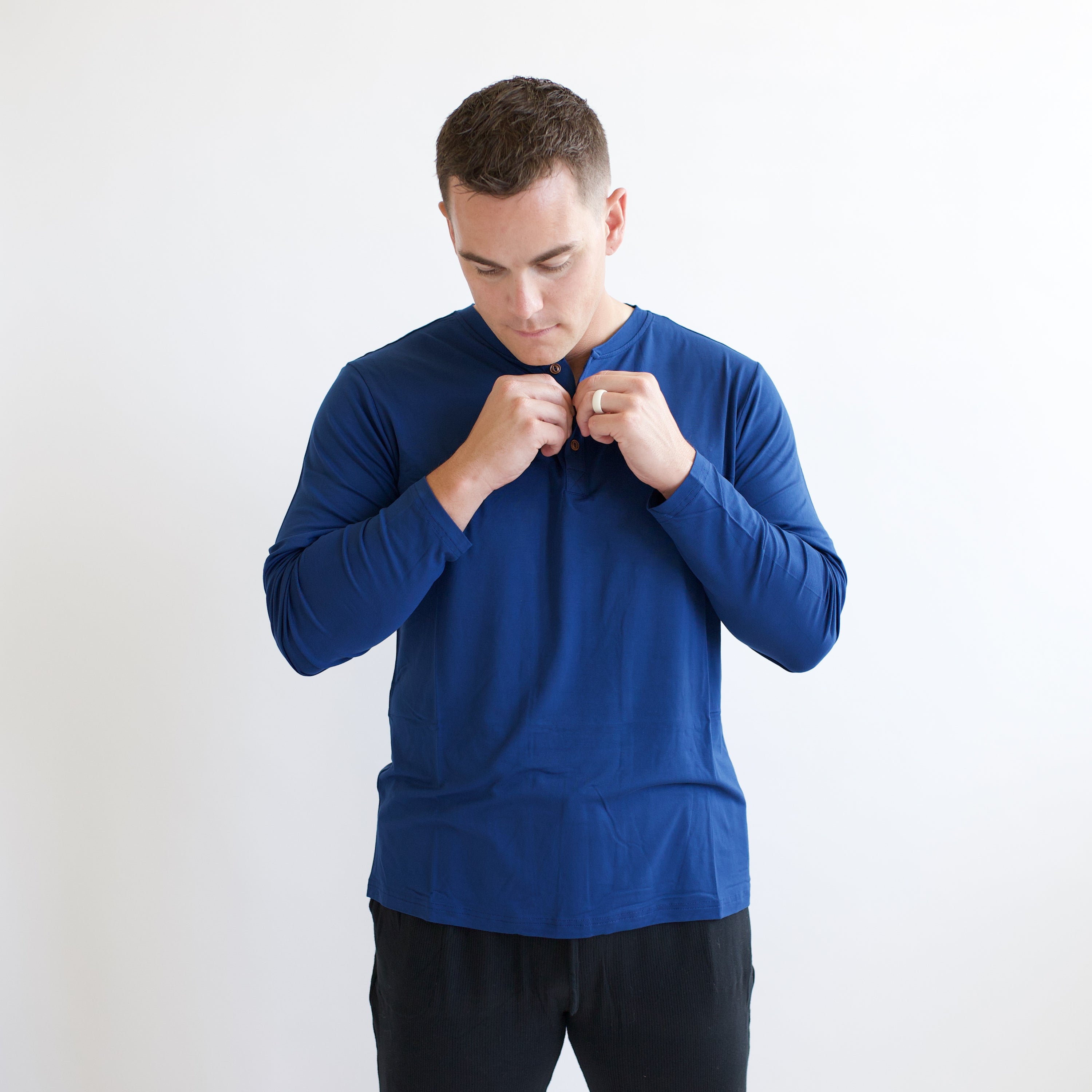 Male model buttoning up the buttons on the Men's Long Sleeve Henley Top in Tahoe