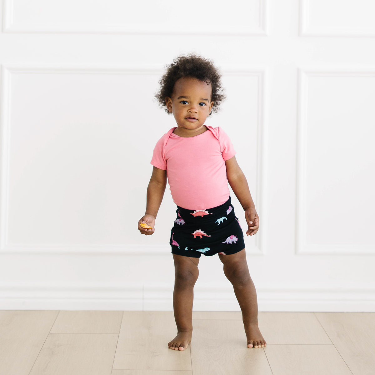 Toddler modeling guava bodysuit and midnight roar bummies