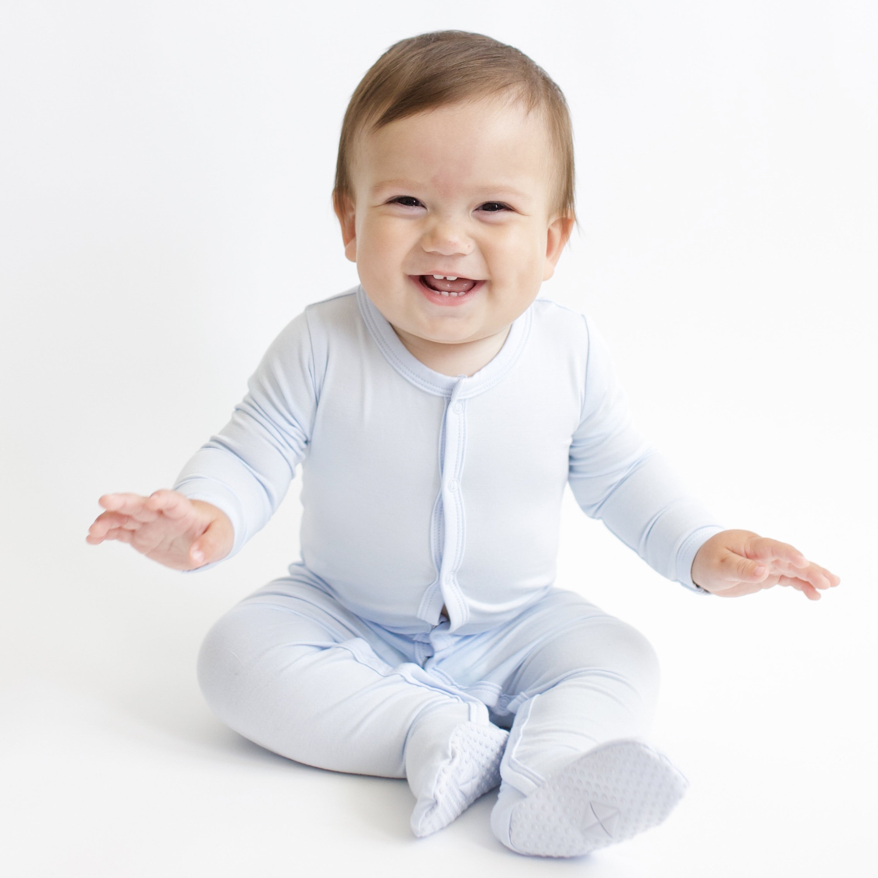 Smiling infant sitting wearing the Footie in Mist
