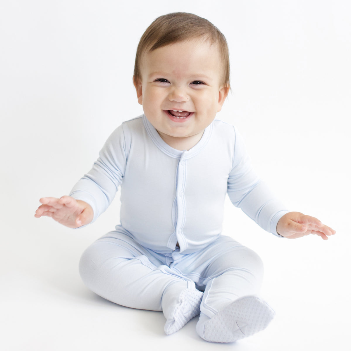 Smiling infant sitting wearing the Footie in Mist