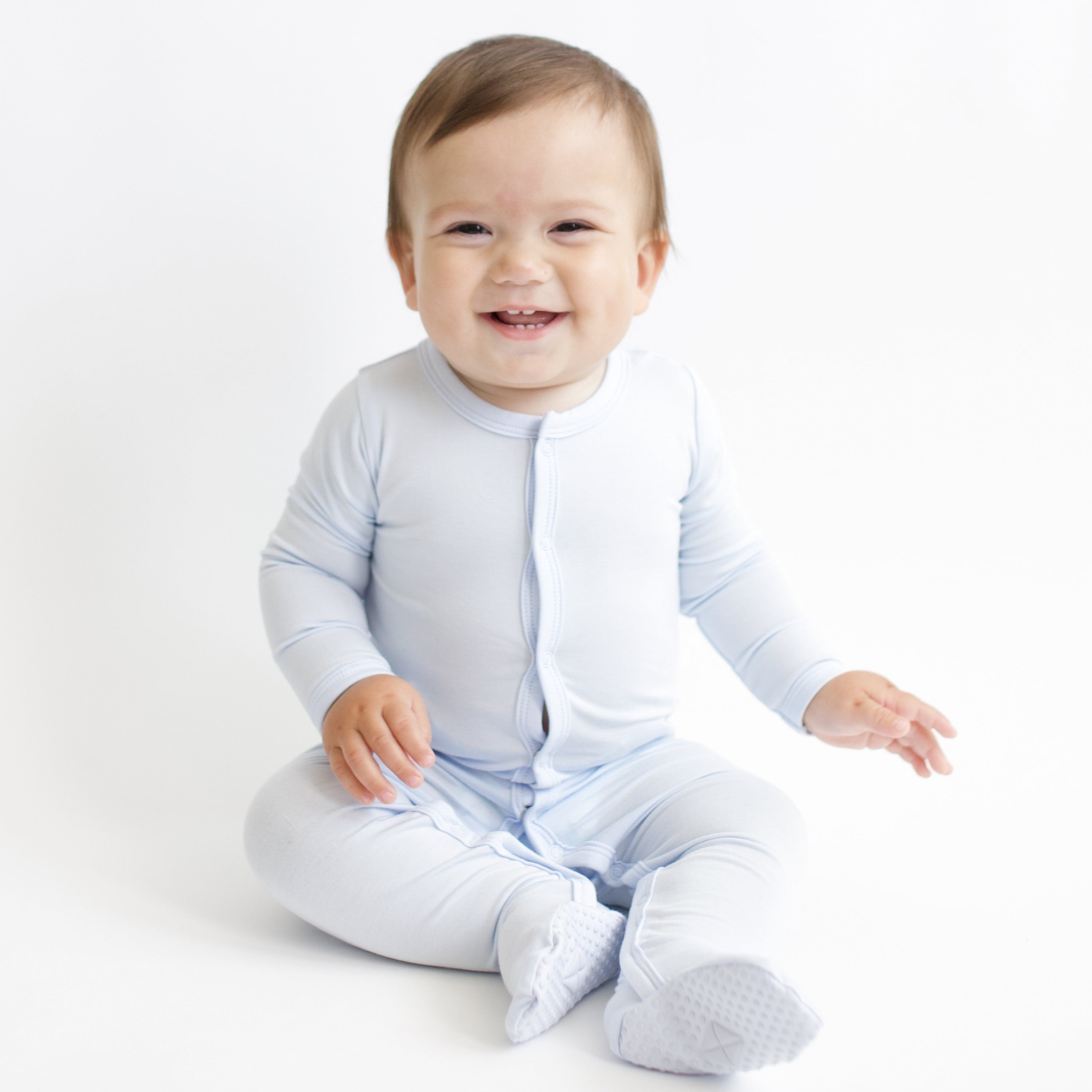 Smiling infant sitting wearing the Footie in Mist