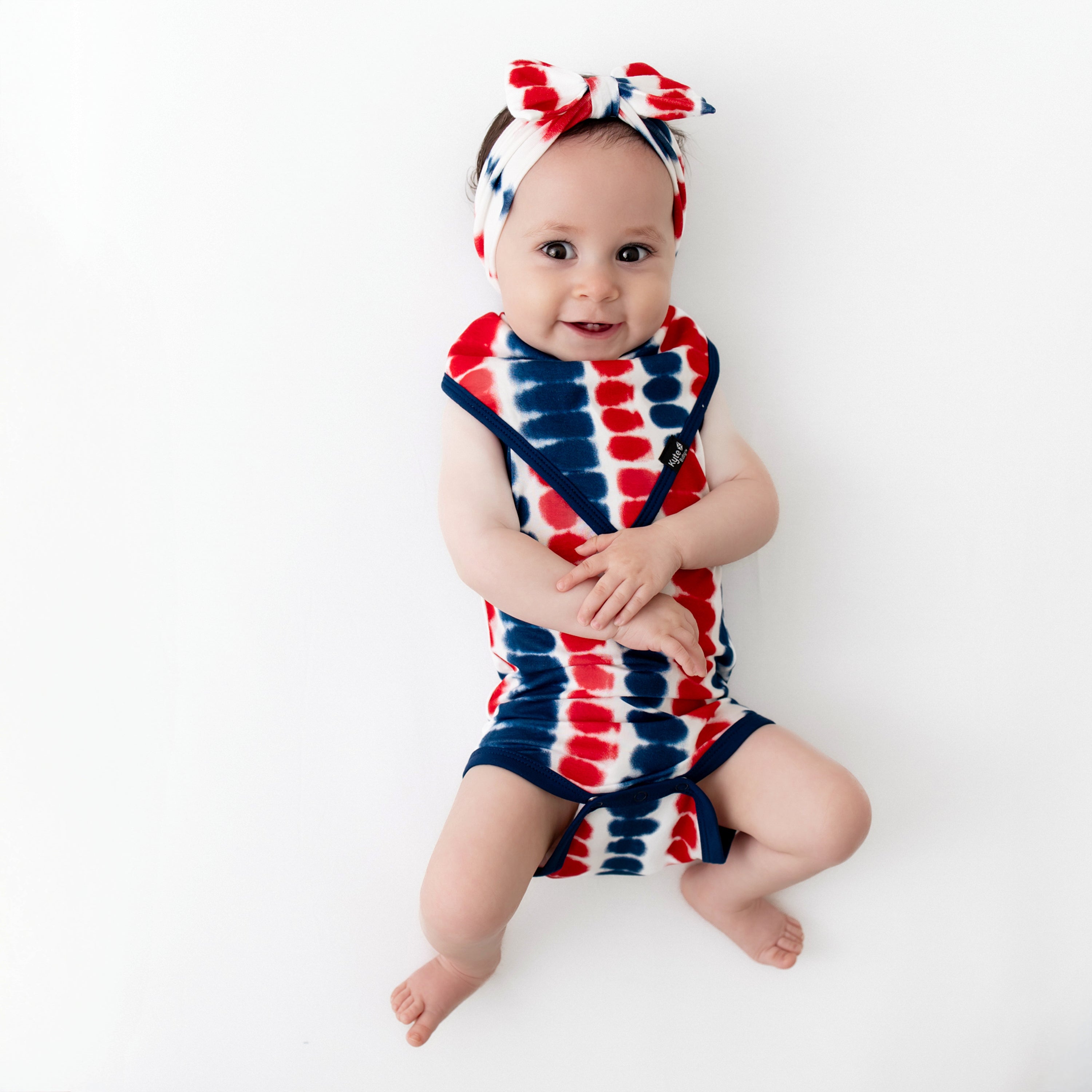 Baby wearing Bow Headband in Liberty Rip Tide and matching Bib and Bodysuit