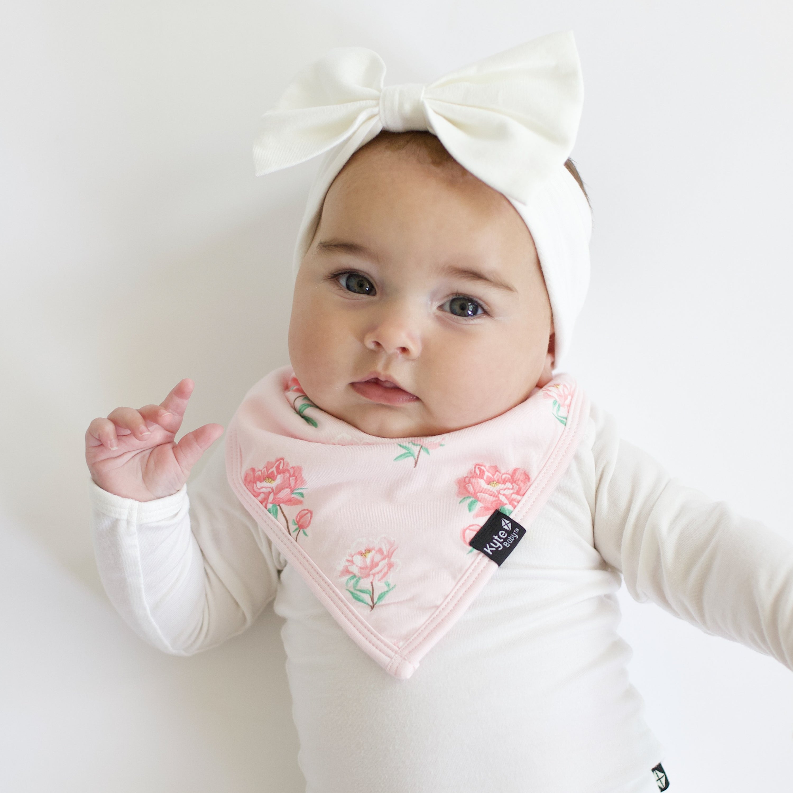 Infant wearing the Bib in Sakura Peony paired with a Cloud long sleeve bodysuit and matching Bow Headband