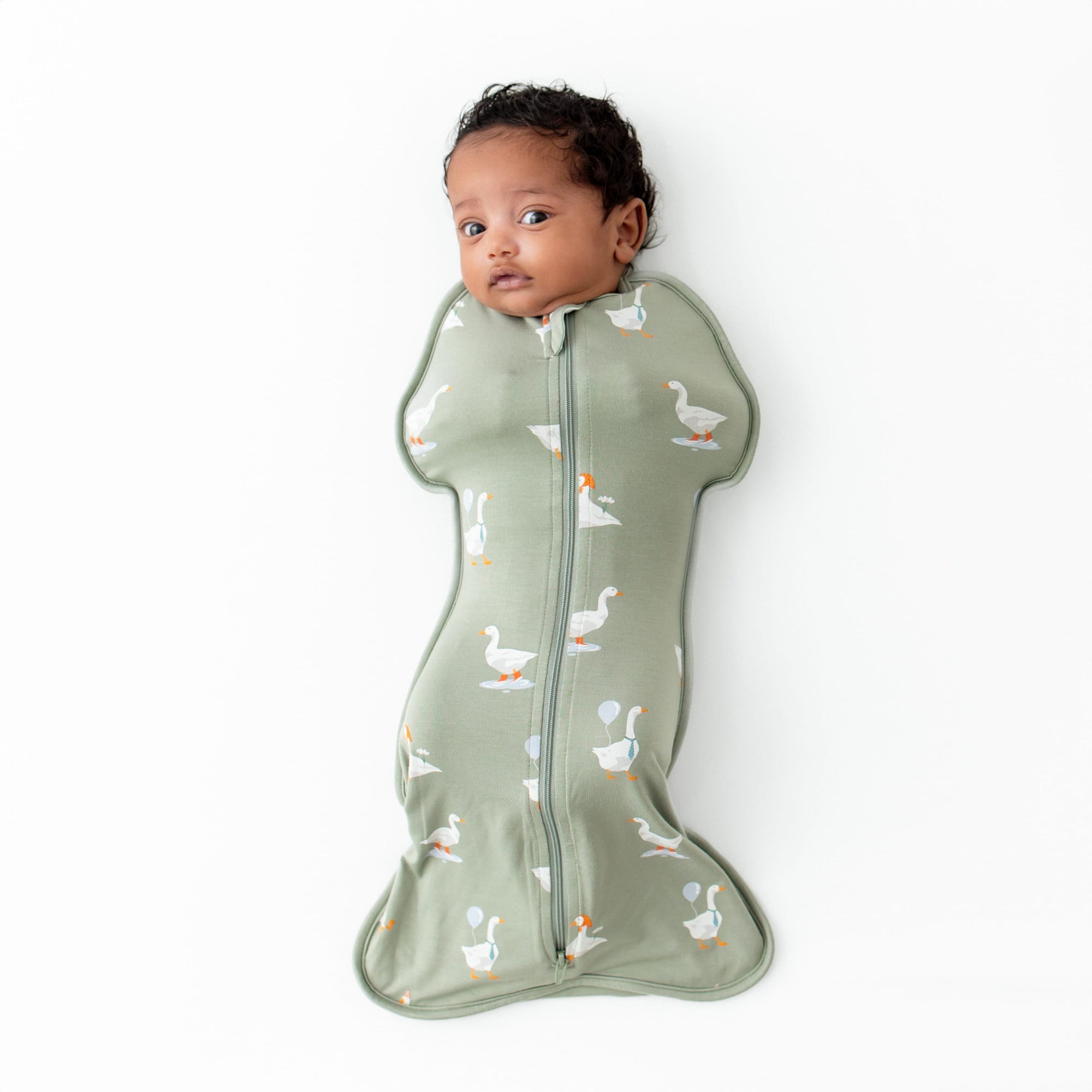Infant laying down wearing the Swaddle Bag in Silly Goose 0.5