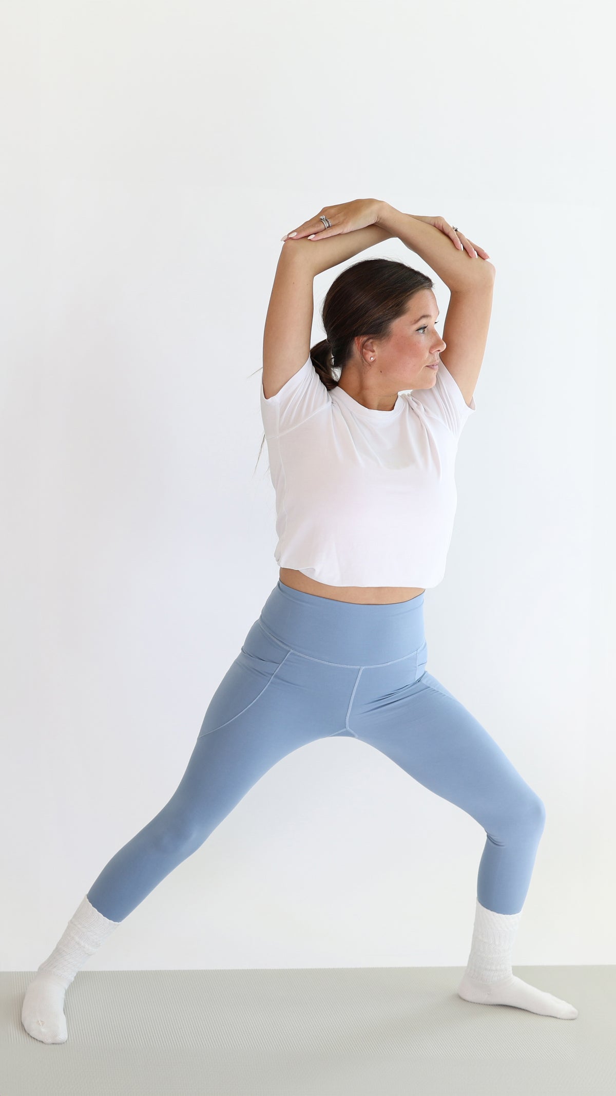 Model stretching wearing the Bamboo Flex Women’s Leggings in Slate standing in front of a white backdrop