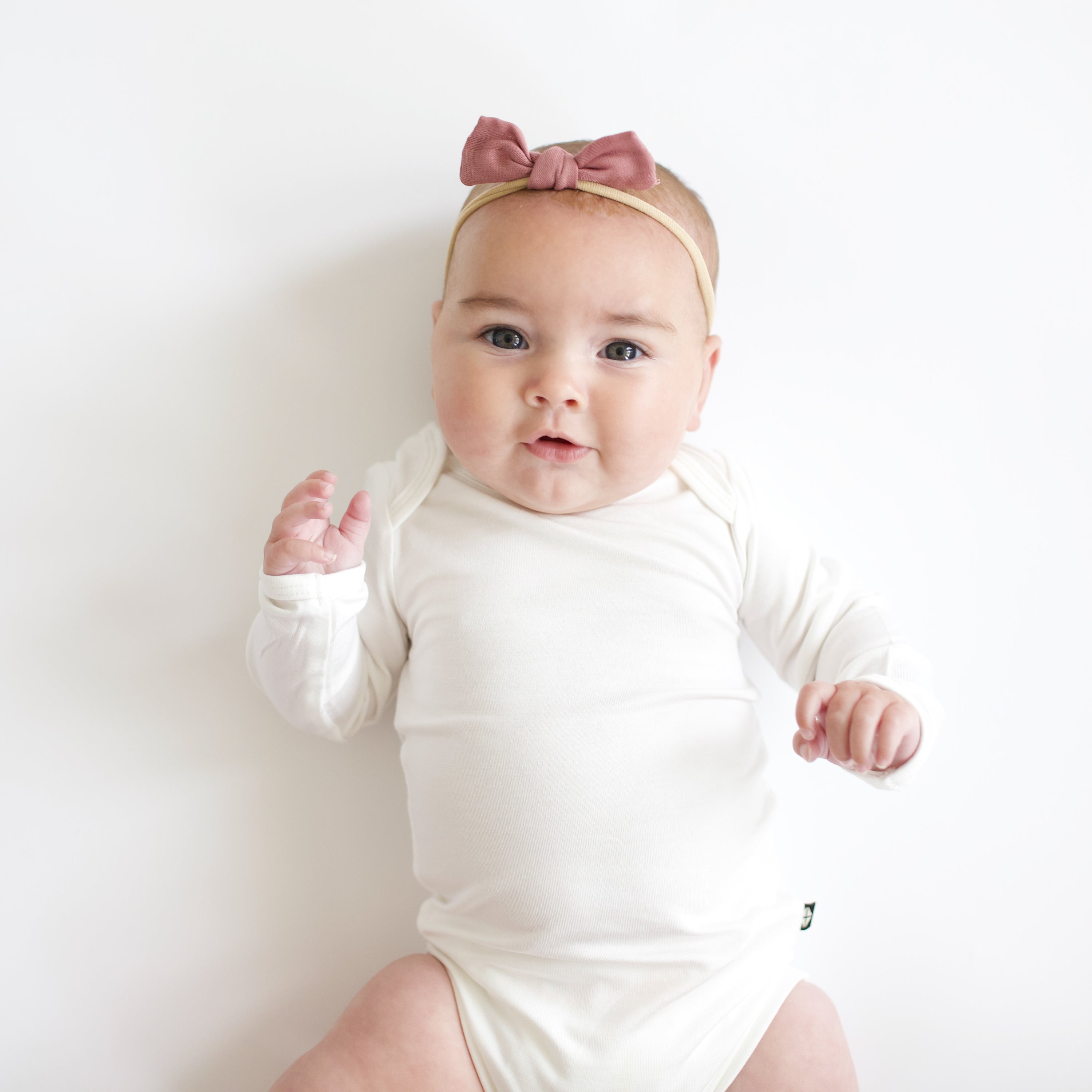 Baby wearing Bamboo Muslin Tiny Bow in Dusty Rose and Cloud Bodysuit