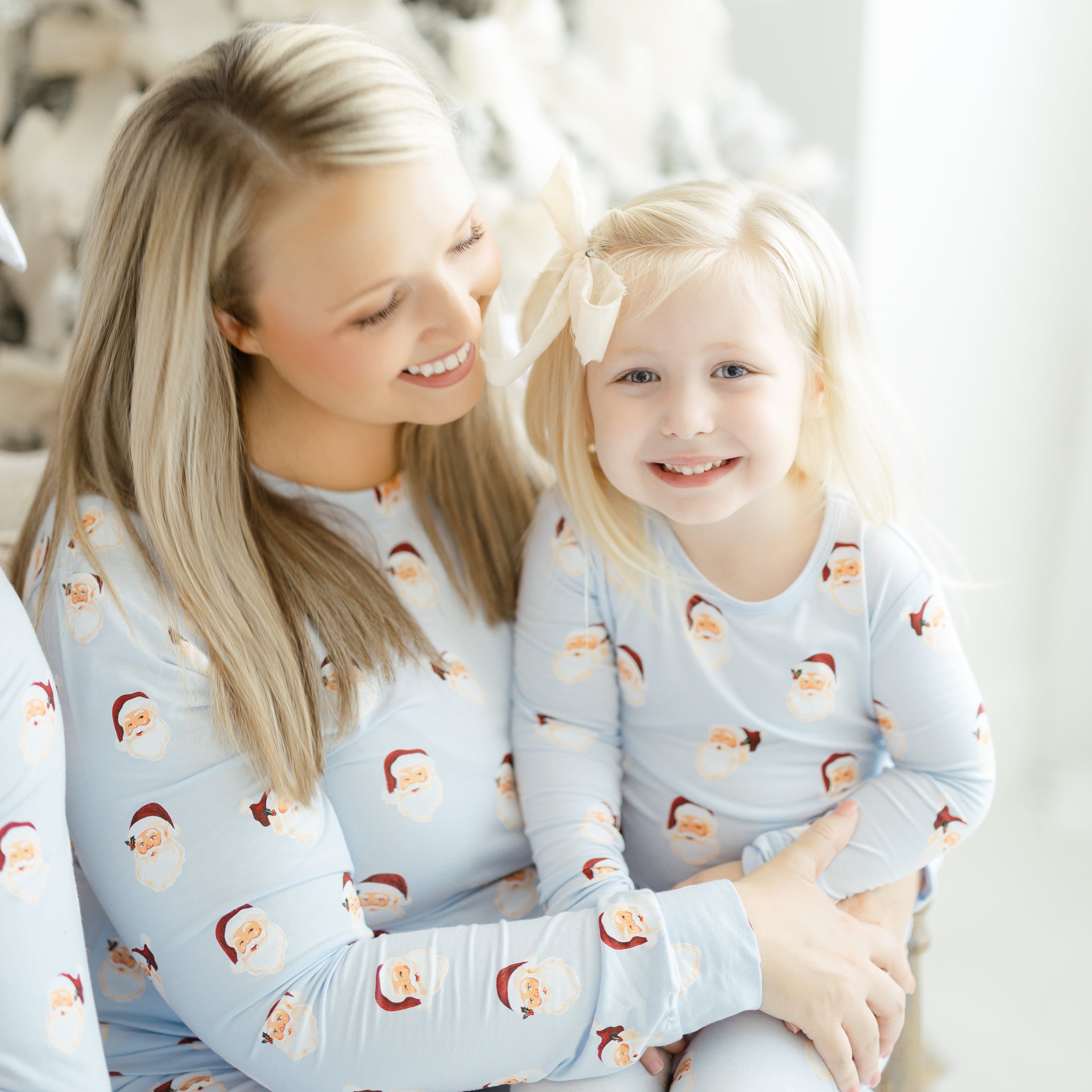 Daughter wearing the Zippered Romper in Vintage Santa sitting on her mothers lap who is matching her in the women's jogger set