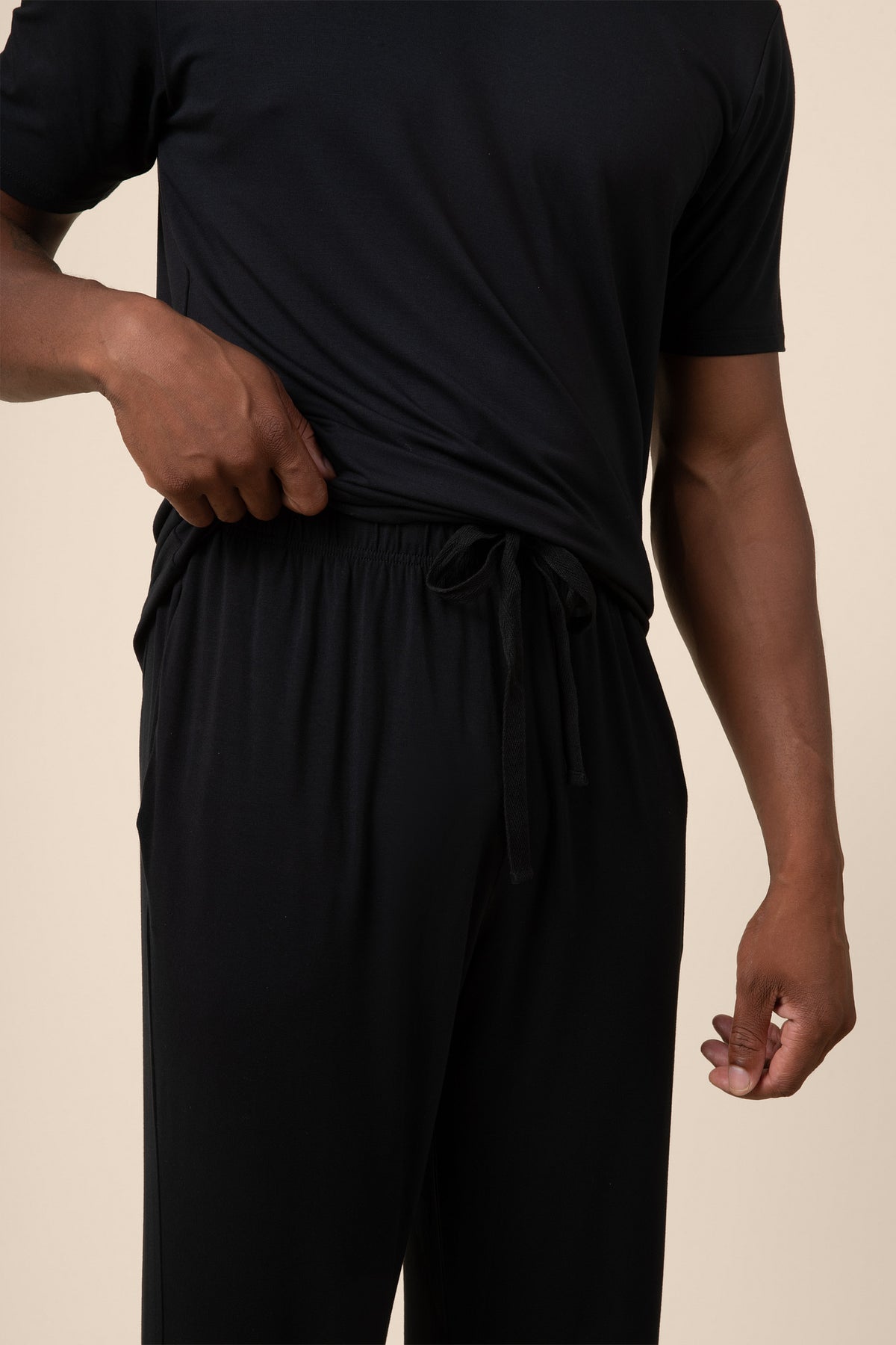 Person wearing a black outfit on a beige background