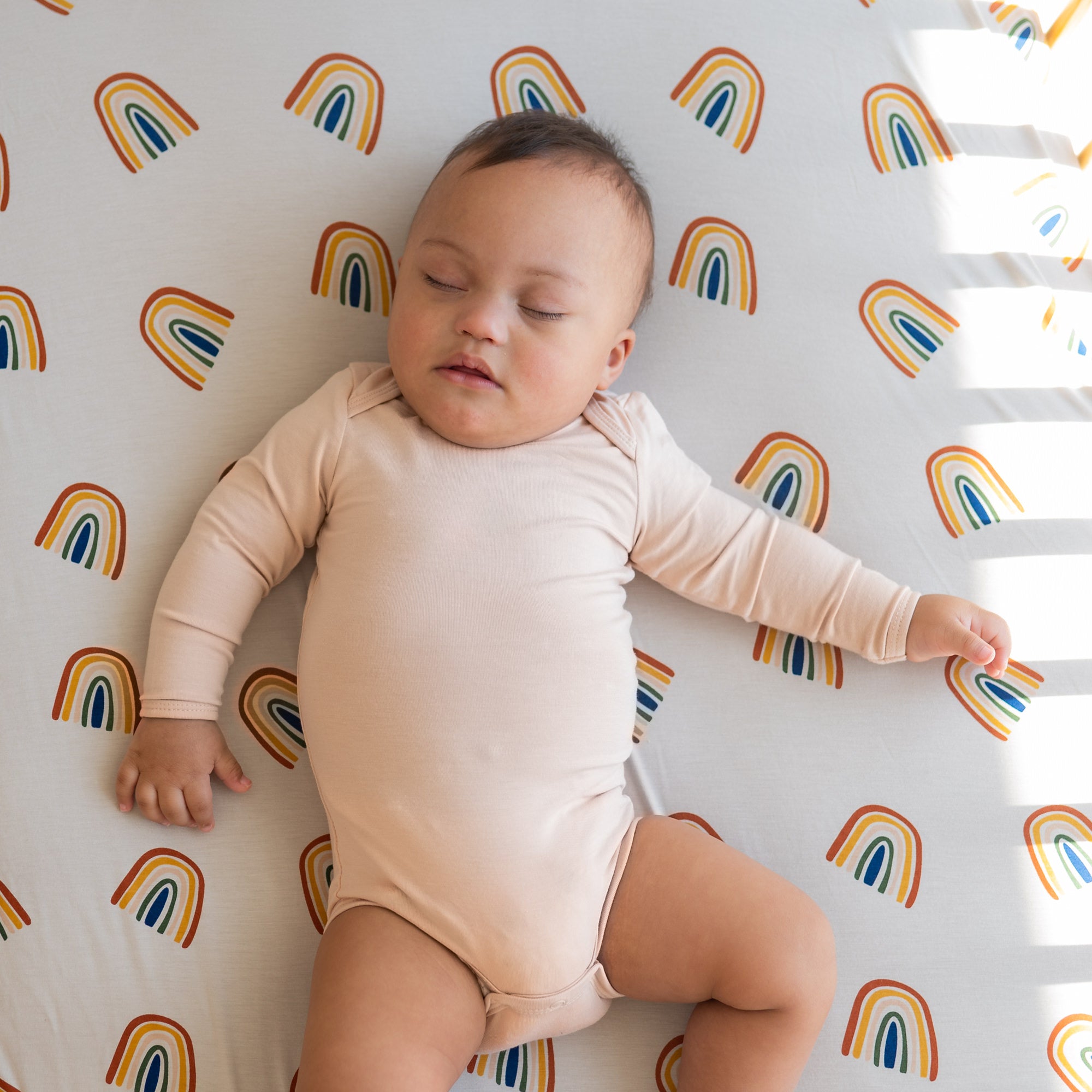Baby sleeping on Bamboo Crib Sheet in Rust Rainbow on Oat