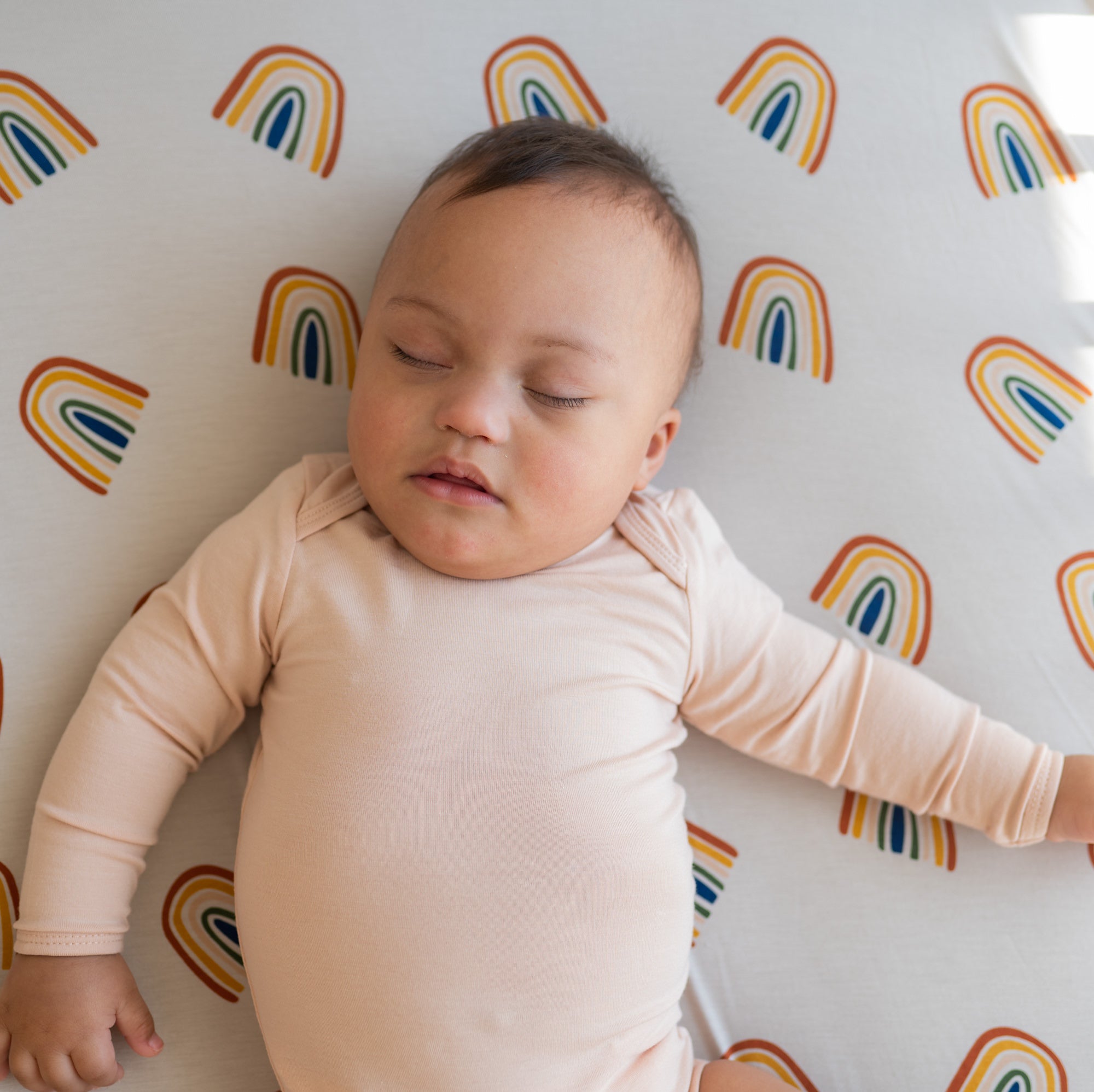 Infant laying on Crib Sheet in Rust Rainbow on Oat