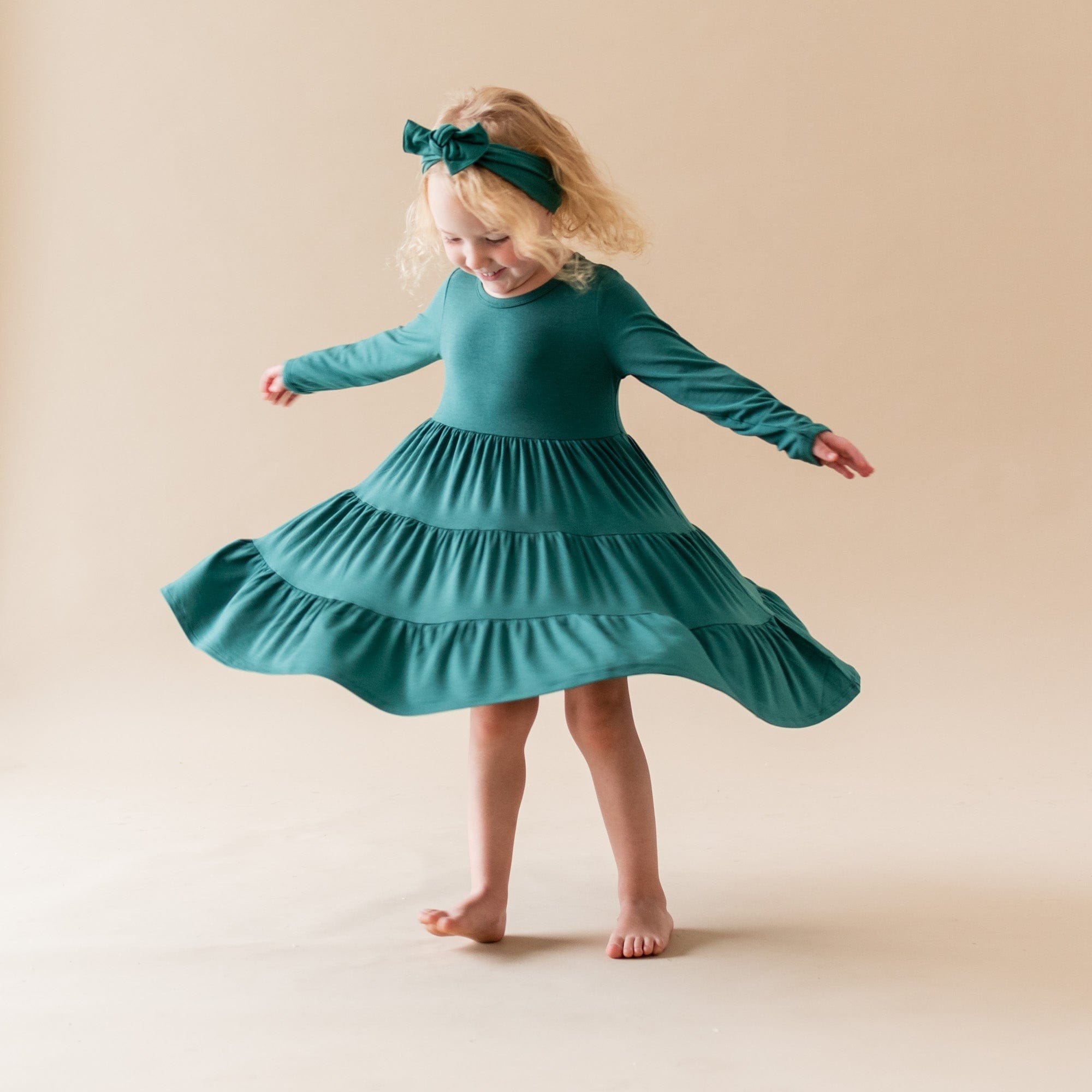 Toddler wearing Kyte Baby bamboo bow headband in Emerald