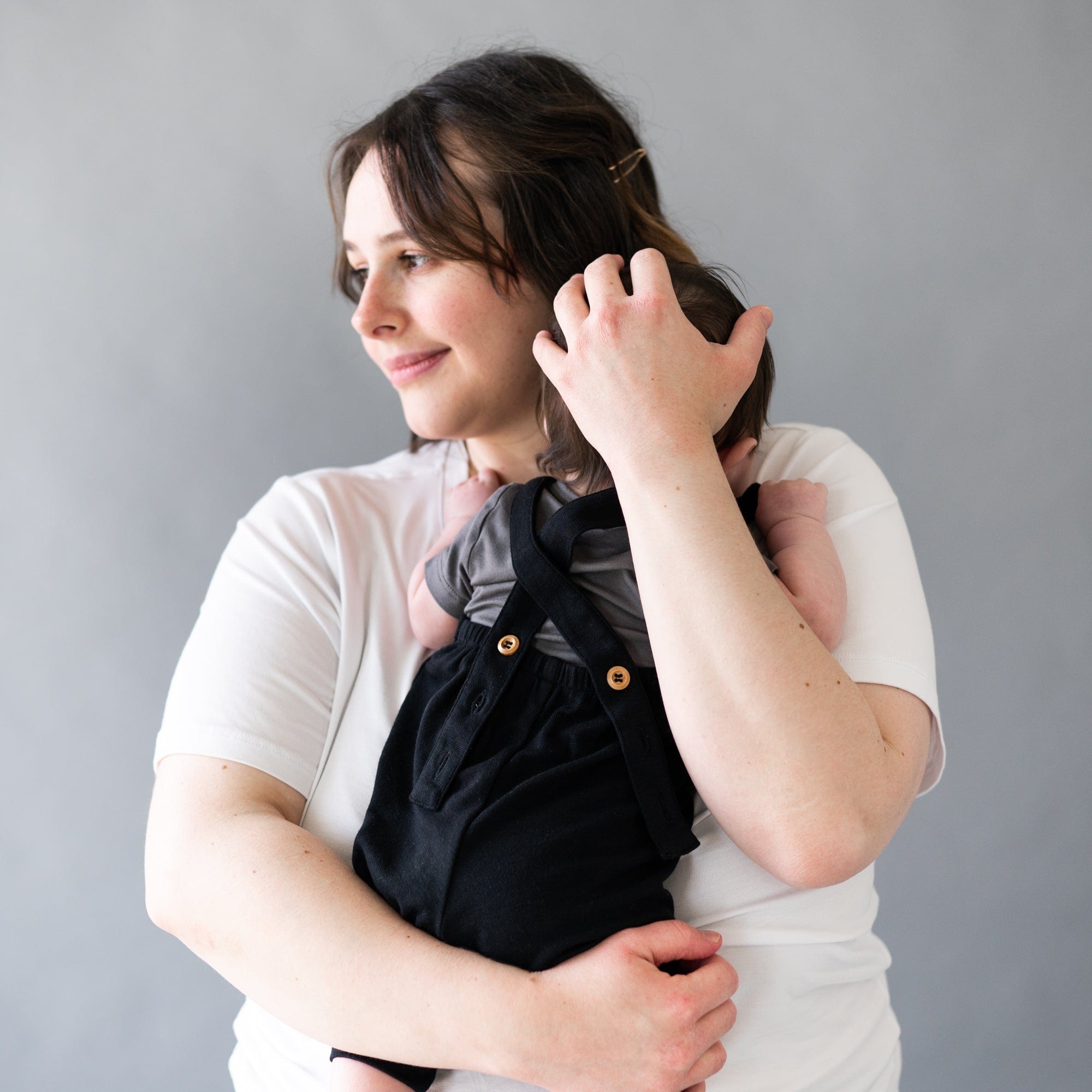 Mom holding infant wearing Kyte Baby Bamboo Jersey Overall in Midnight