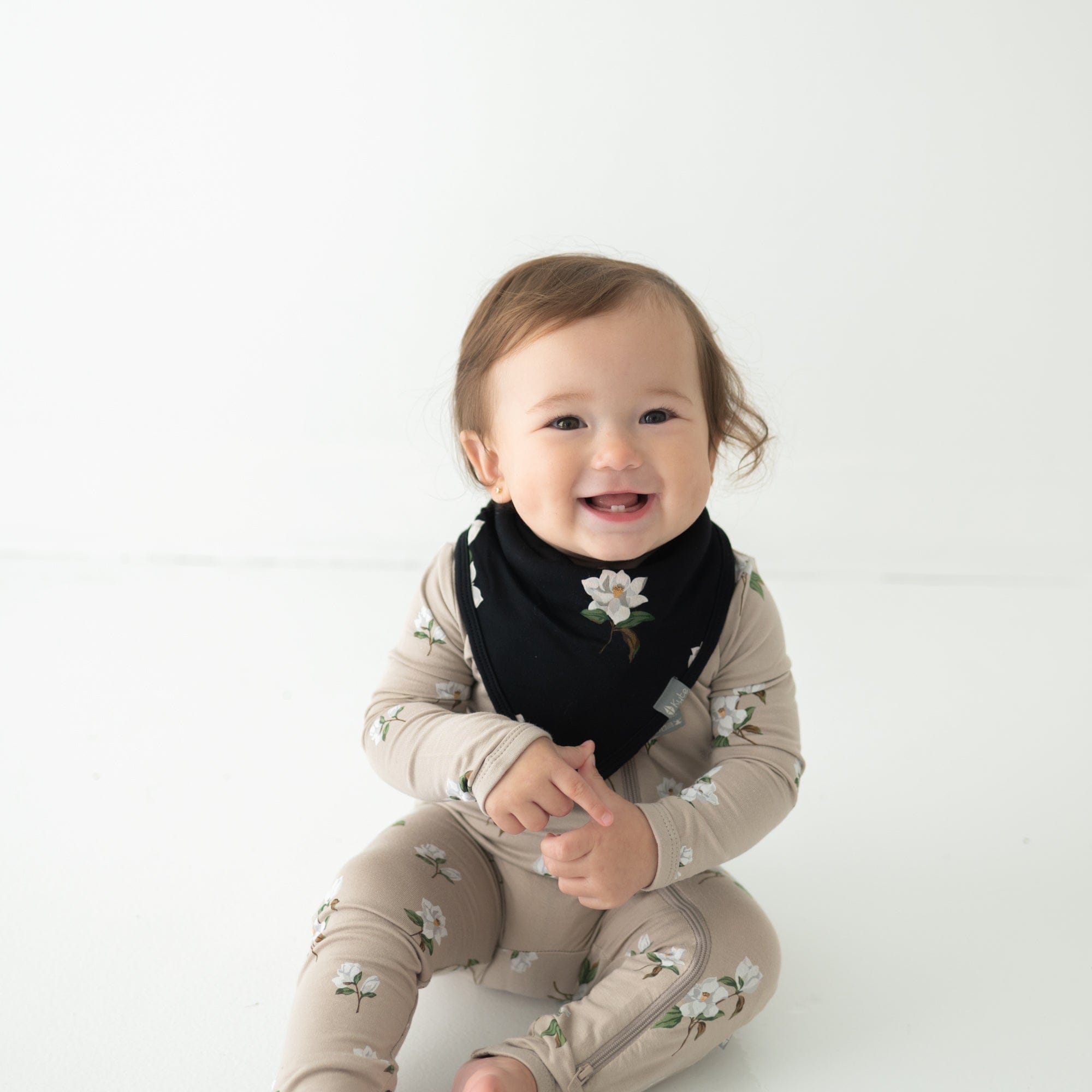 Infant wearing Kyte Baby Bib in Big Midnight Magnolia