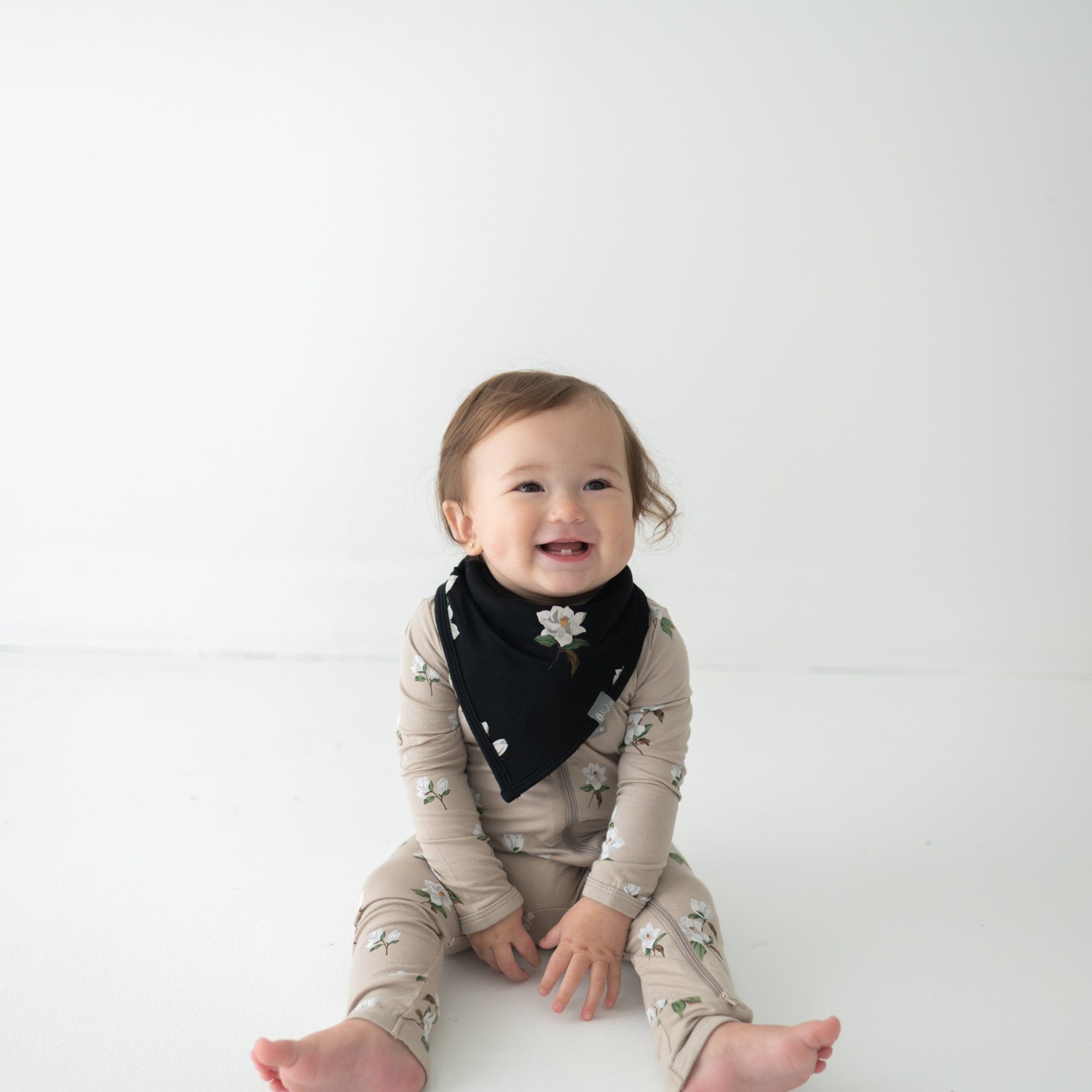 Infant wearing Kyte Baby bamboo Bib in Big Midnight Magnolia