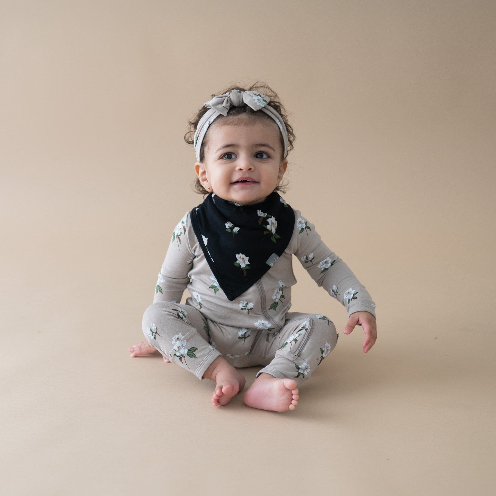 Infant wearing Kyte Baby Bib in Small Magnolia on Midnight