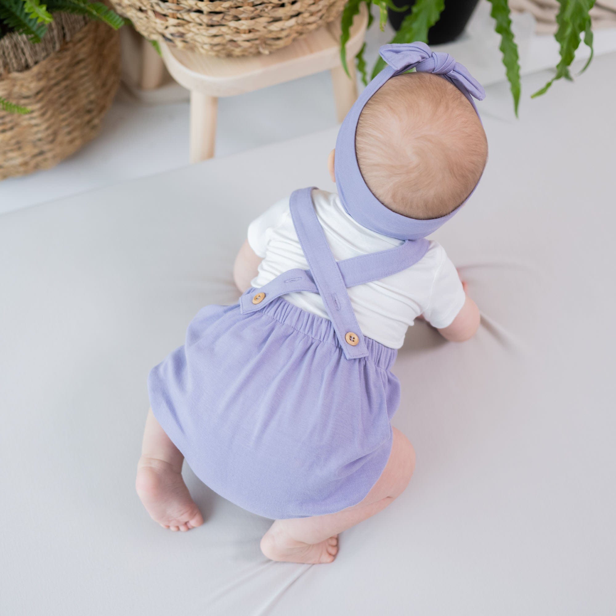 Infant wearing Kyte Baby Bamboo Jersey Bubble Overall with Crossover Straps in Taro purple