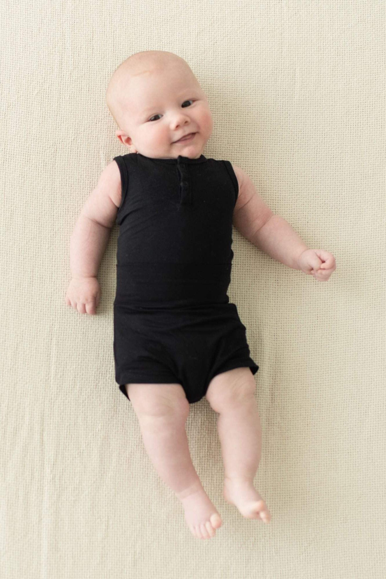 Smiling infant wearing Kyte Baby Bummies in Midnight and matching bodysuit