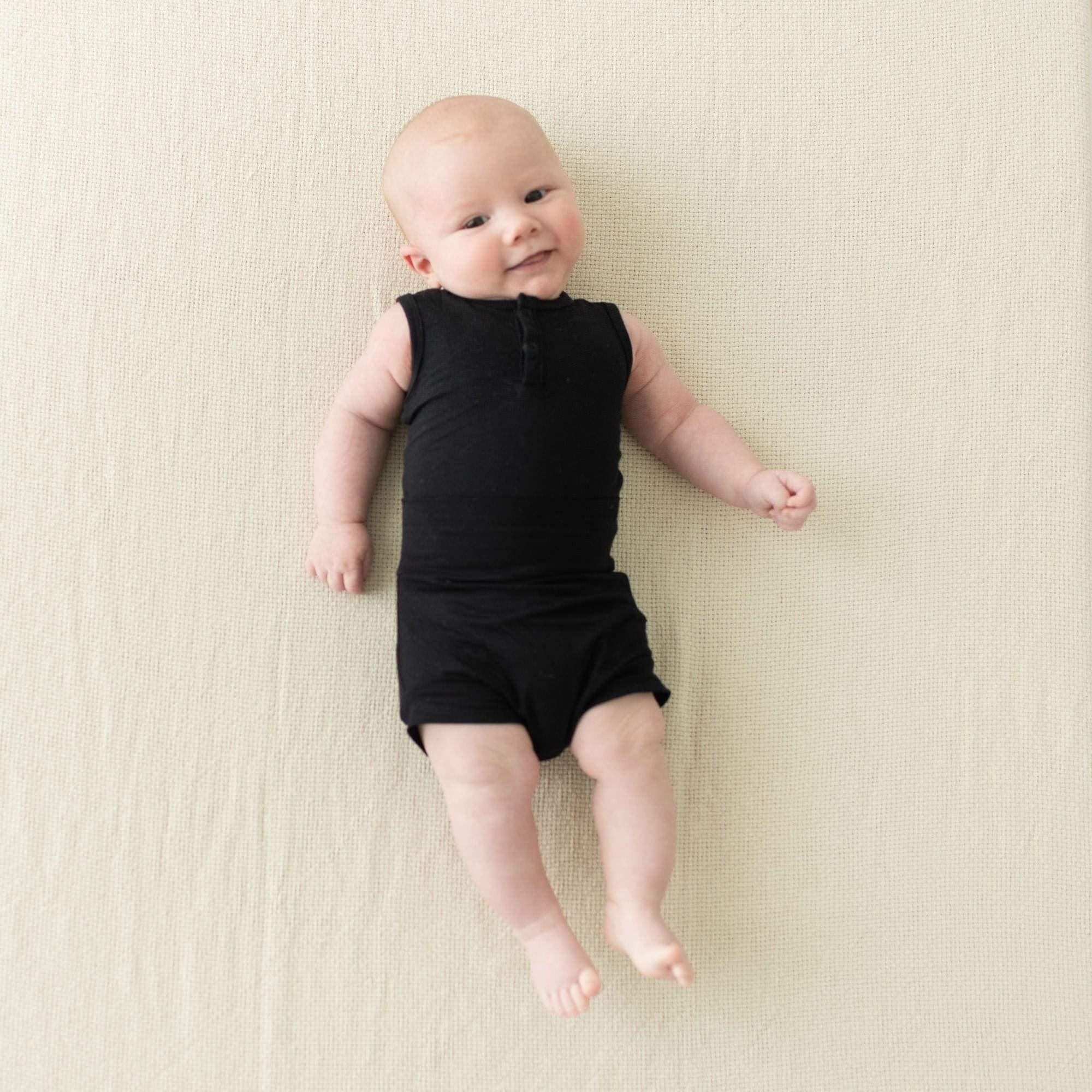 Smiling infant wearing Kyte Baby Bummies in Midnight and matching bodysuit