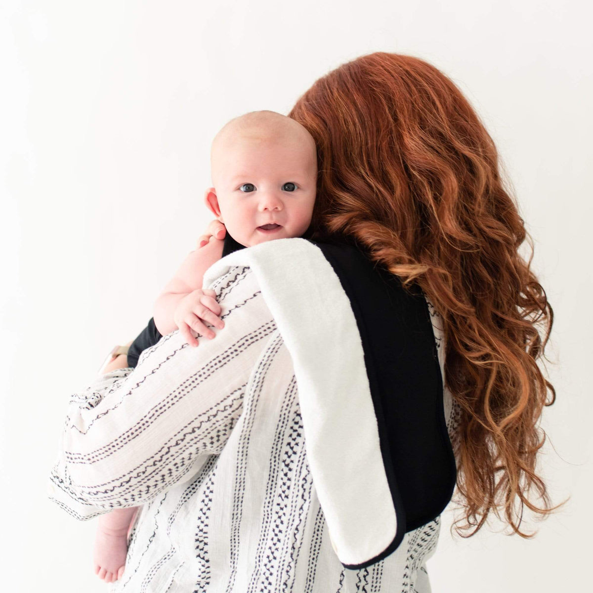 Mom burping infant using Kyte Baby Burp Cloth in Midnight
