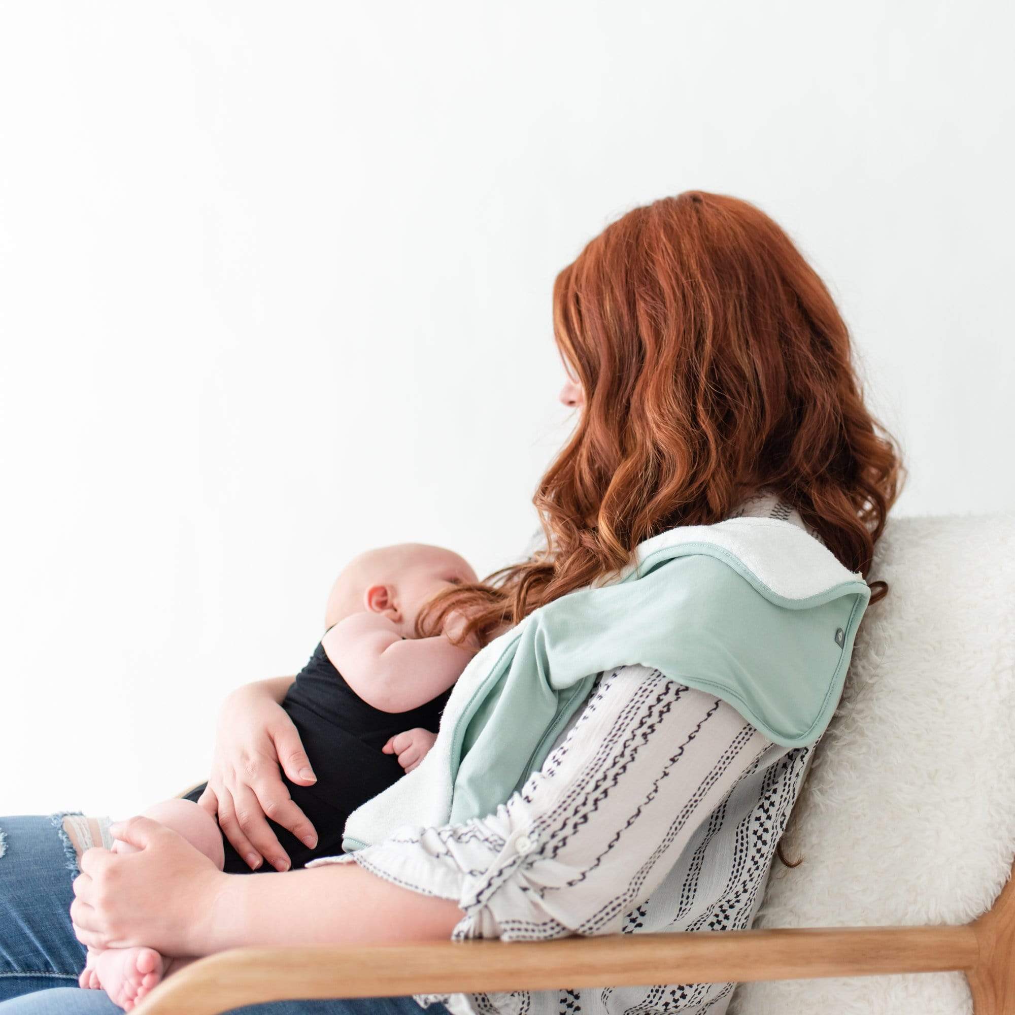 Mom nursing infant with Burp Cloth in sage placed on her shoulder