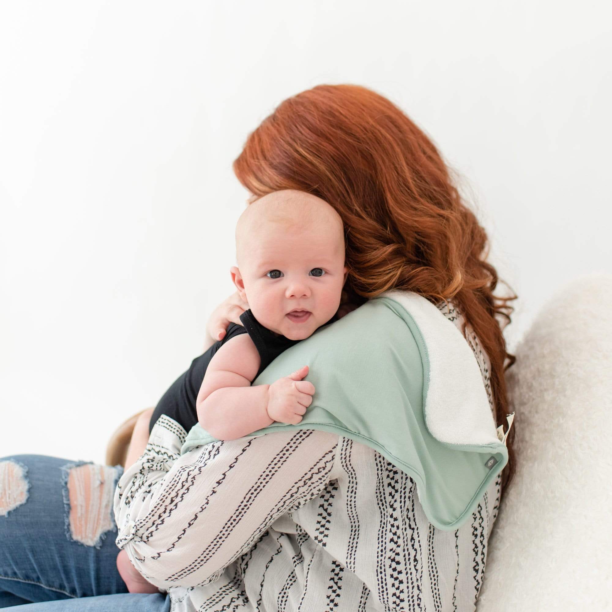 Mom burping infant using Kyte Baby Burp Cloth in Sage
