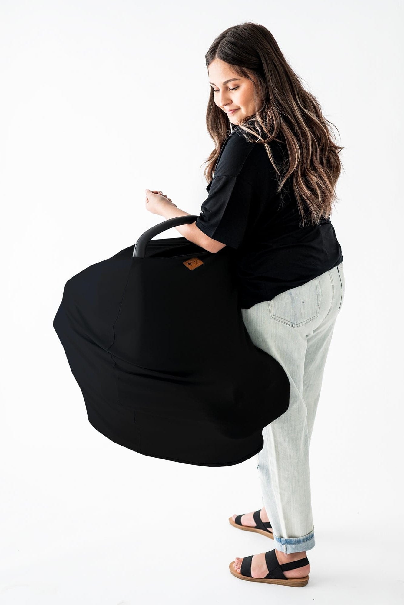 Mom carrying infant seat with Kyte Baby Car Seat Cover in Midnight