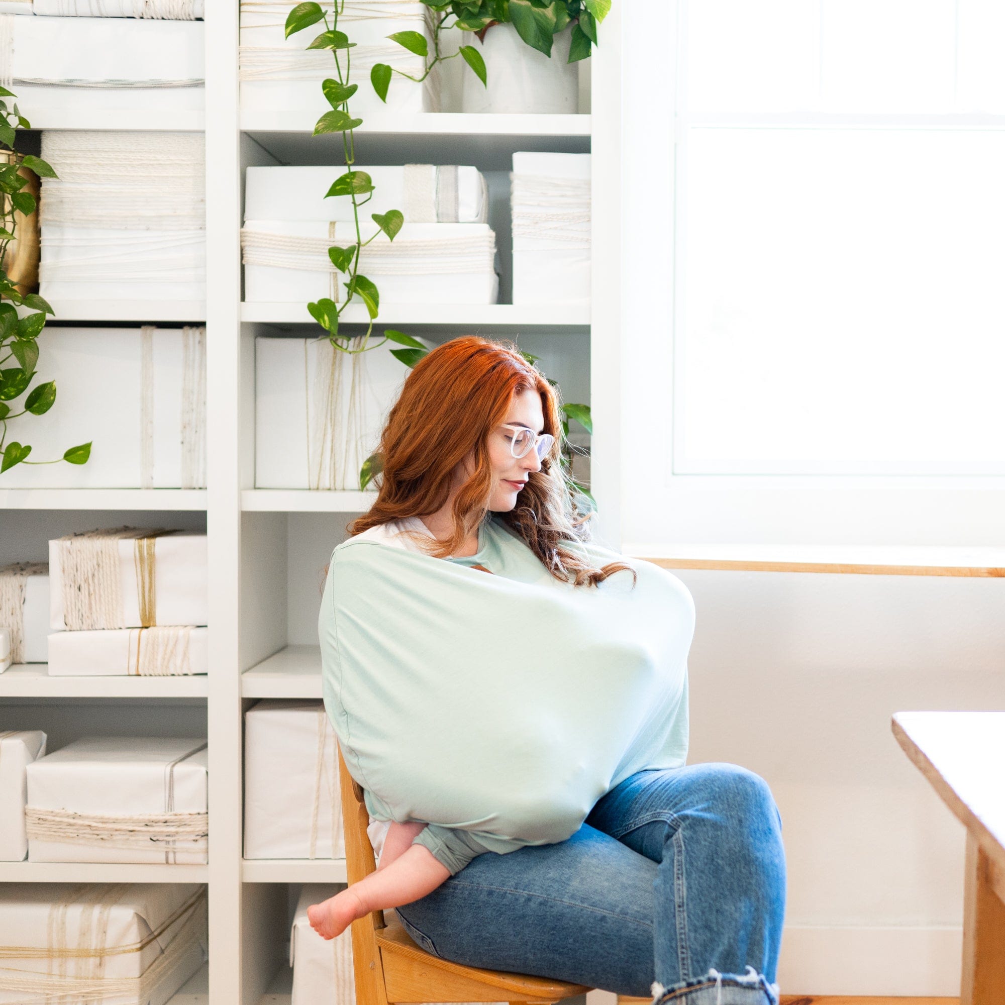 Mother using Kyte Baby car seat and nursing cover in Sage