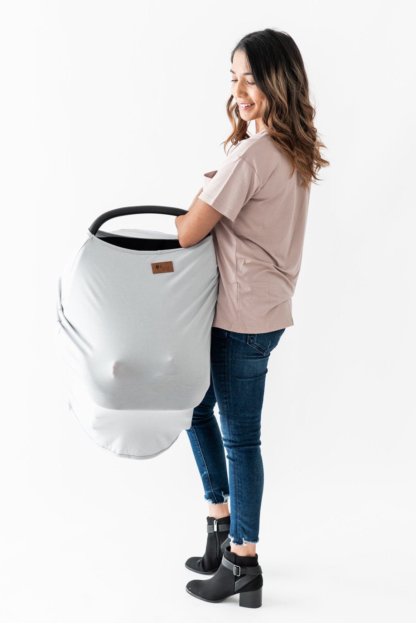 Mom carrying infant carrier covered with Kyte Baby bamboo Car Seat Cover in Storm