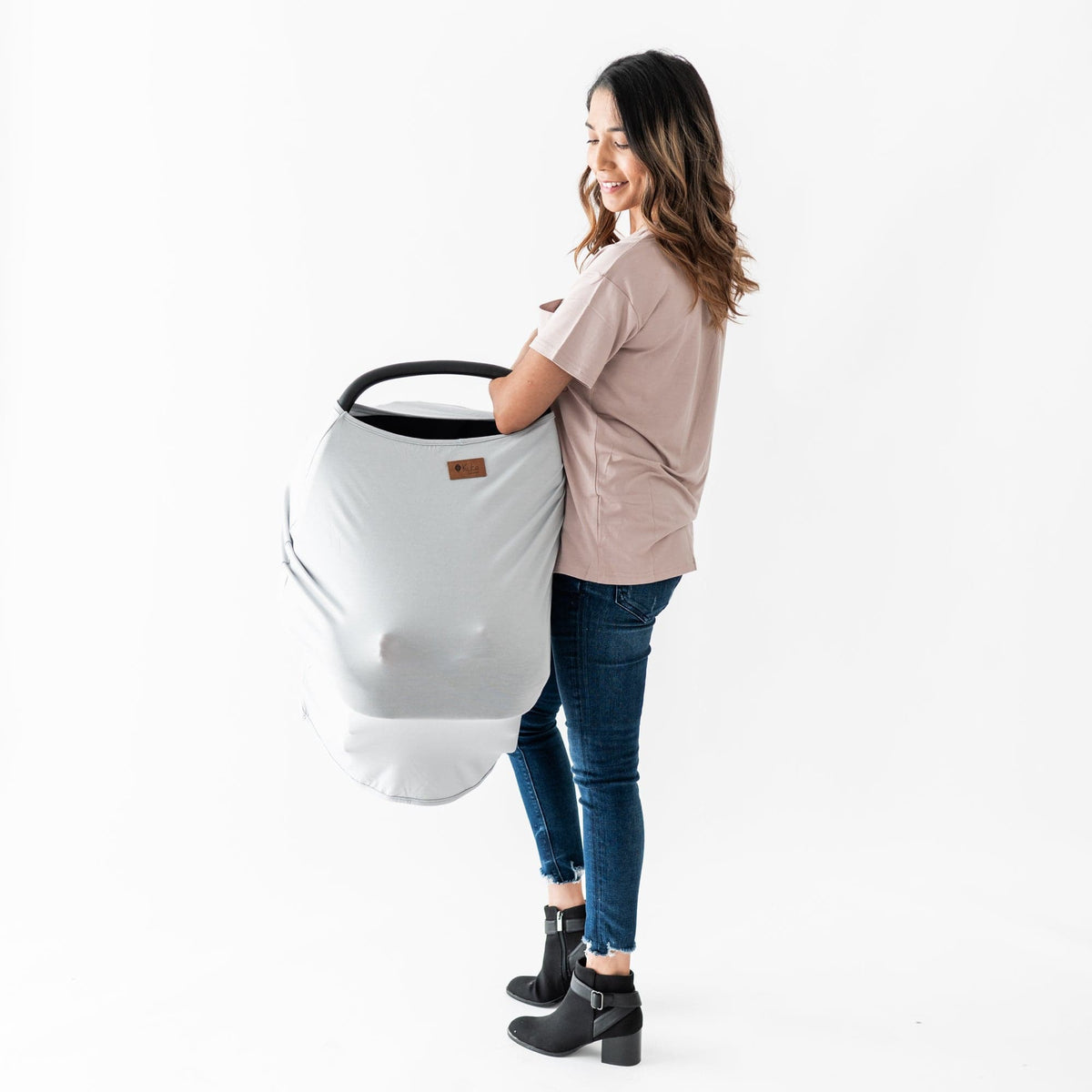 Mom carrying infant carrier covered with Kyte Baby bamboo Car Seat Cover in Storm