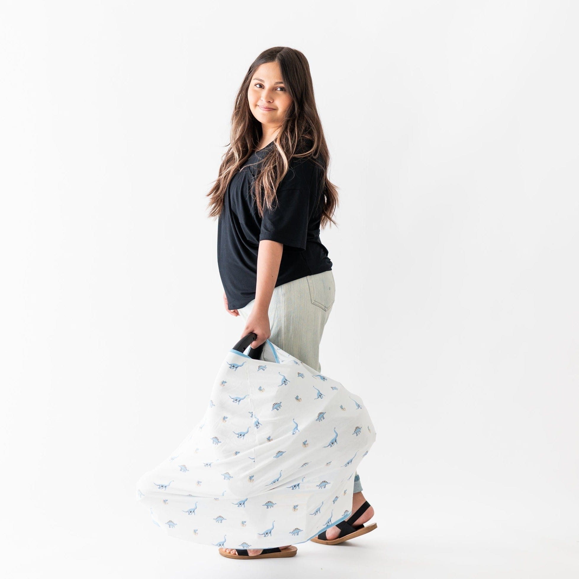 Woman carrying carseat with Kyte Baby bamboo Infant Seat Cover in Jurassic