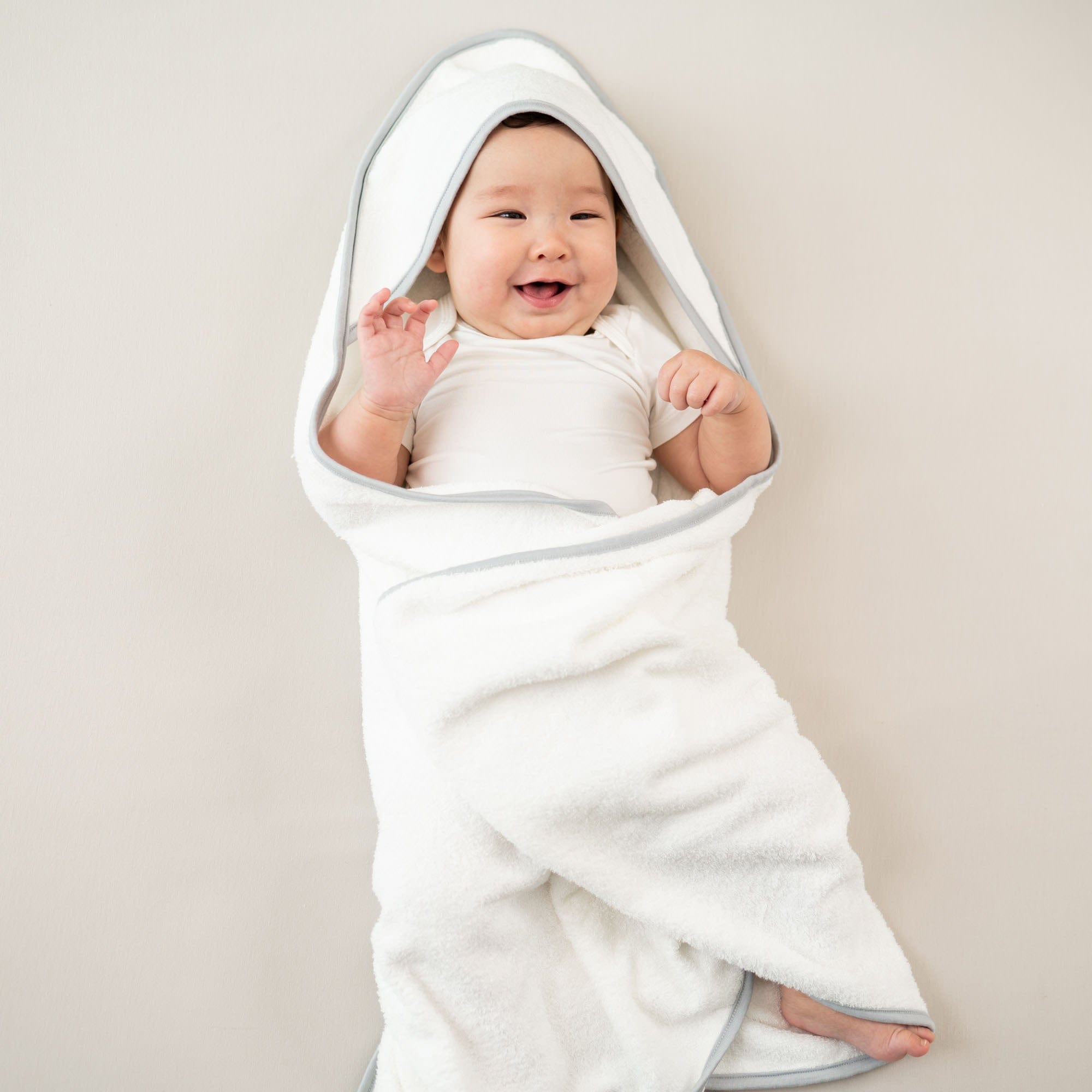 Child wrapped in Kyte Baby Hooded Bath Towel in Cloud with Storm Trim