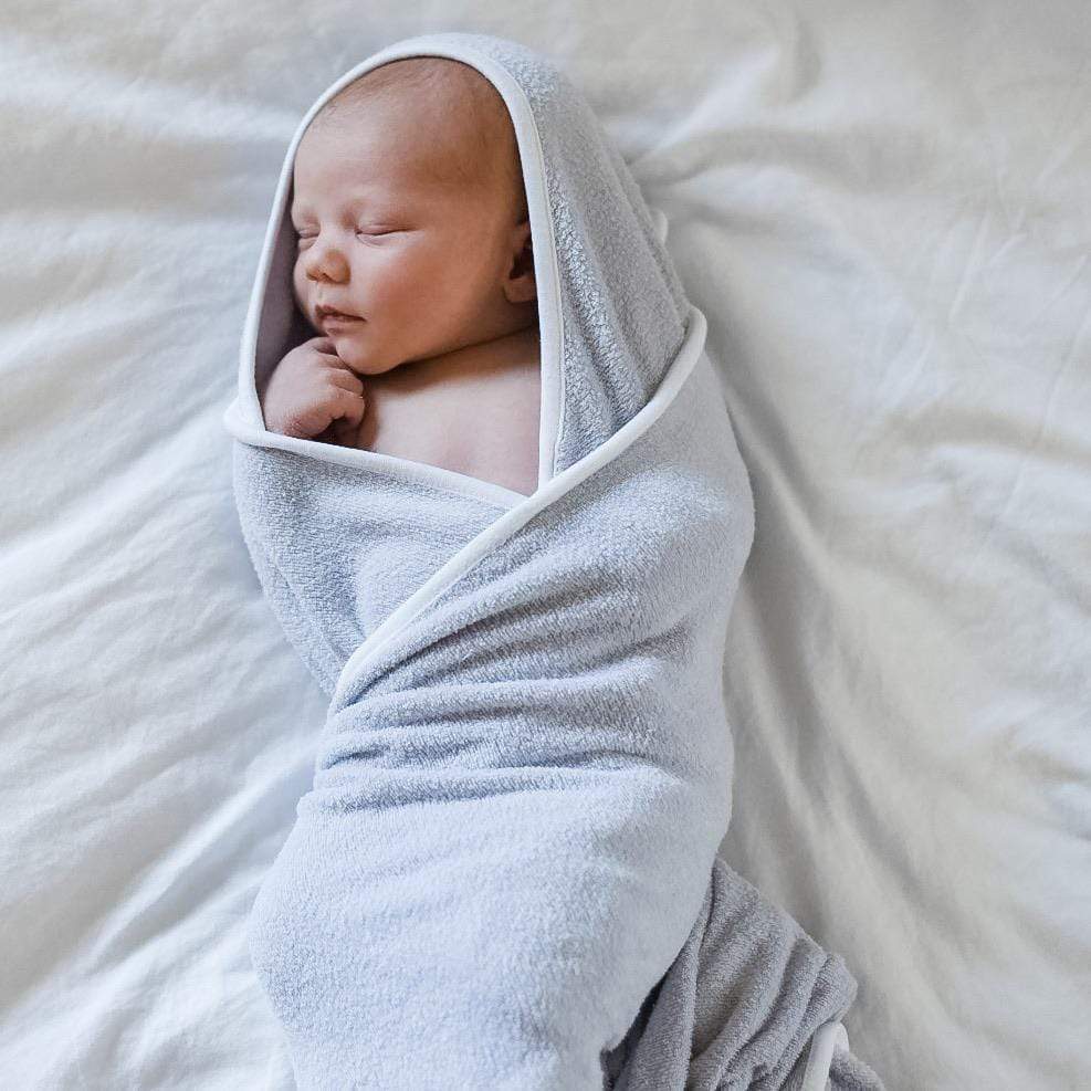 Newborn wrapped in Kyte Baby Hooded Bath Towel in Storm with Cloud Trim