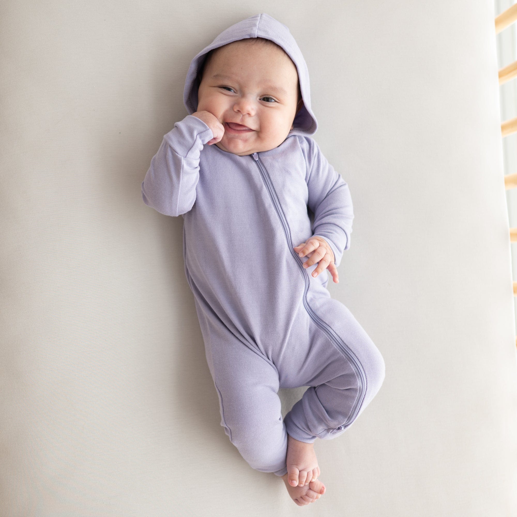 Infant wearing Kyte Baby Bamboo Jersey Hooded Zippered Romper in Taro