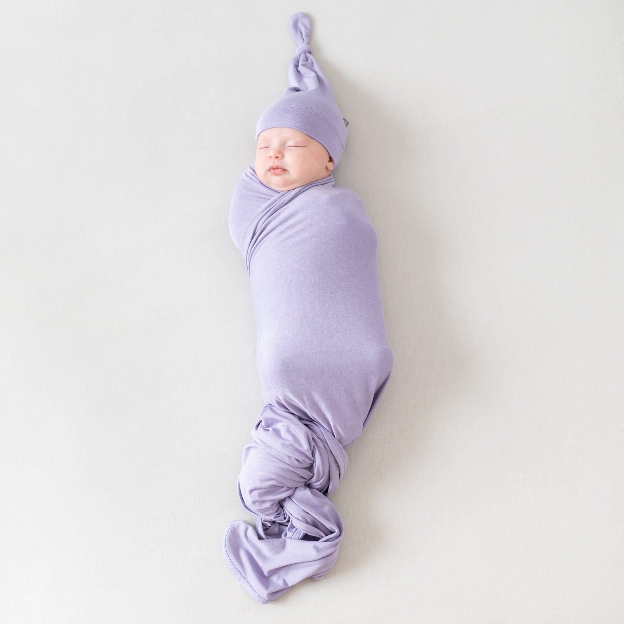 Sleeping infant wrapped in swaddle blanket and wearing a knotted cap in Taro