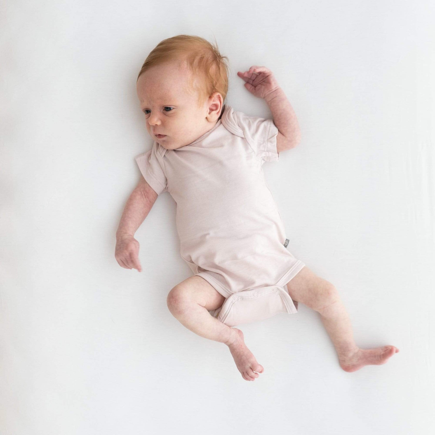 Baby wearing Kyte Baby infant Bodysuit in Blush