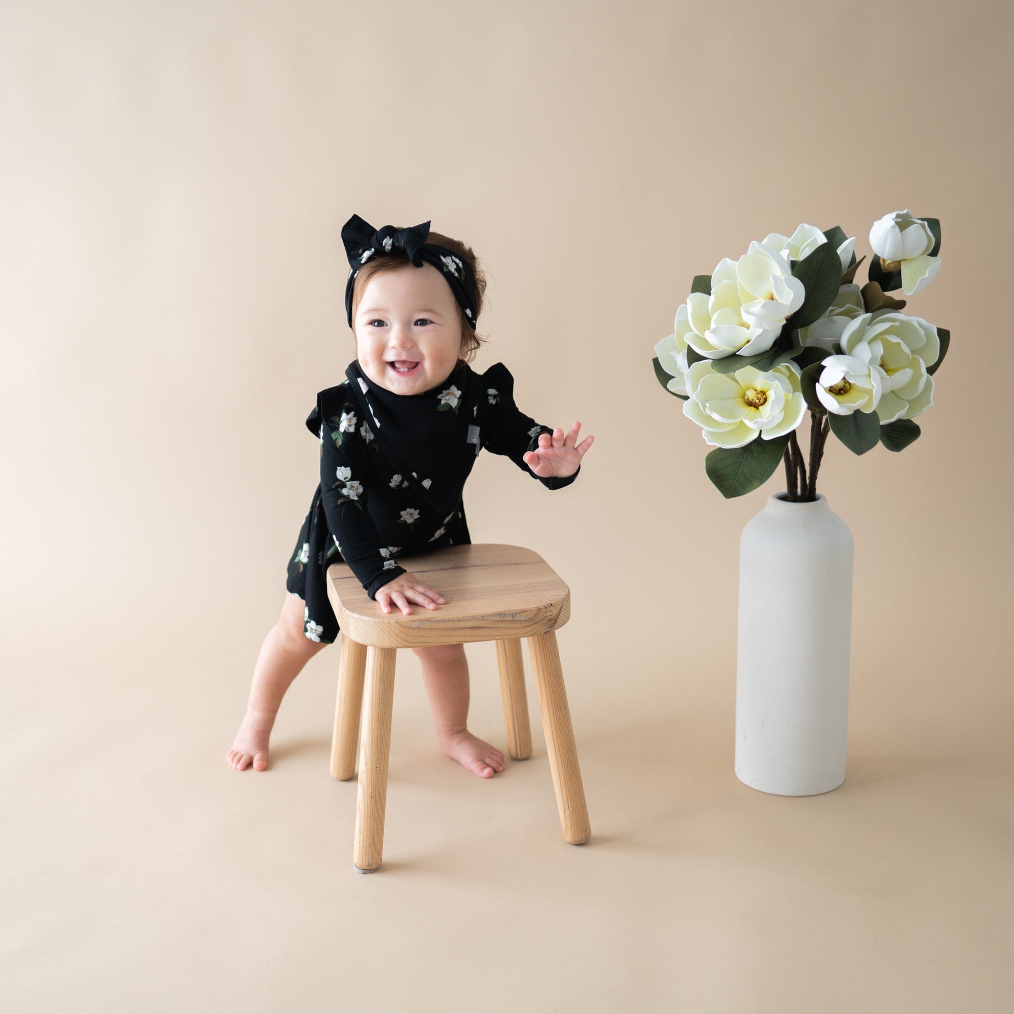 Infant wearing Kyte Baby Long Sleeve Twirl Bodysuit Dress with snaps in Small Midnight Magnolia