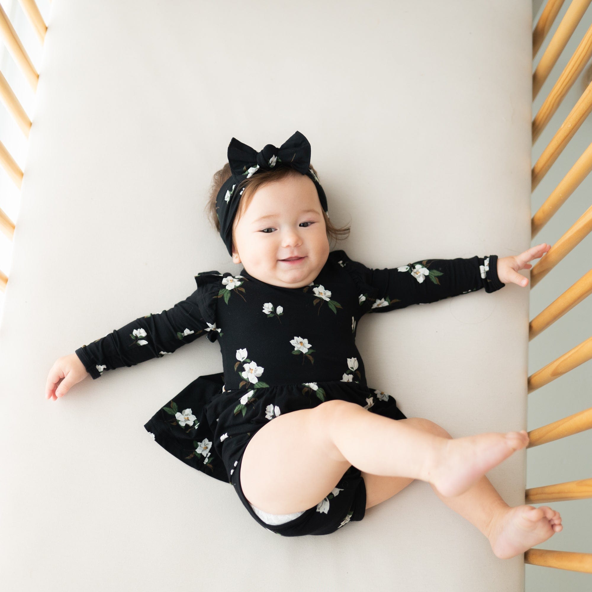 Baby wearing Kyte Baby Long Sleeve infant Twirl Bodysuit Dress in Small Midnight Magnolia